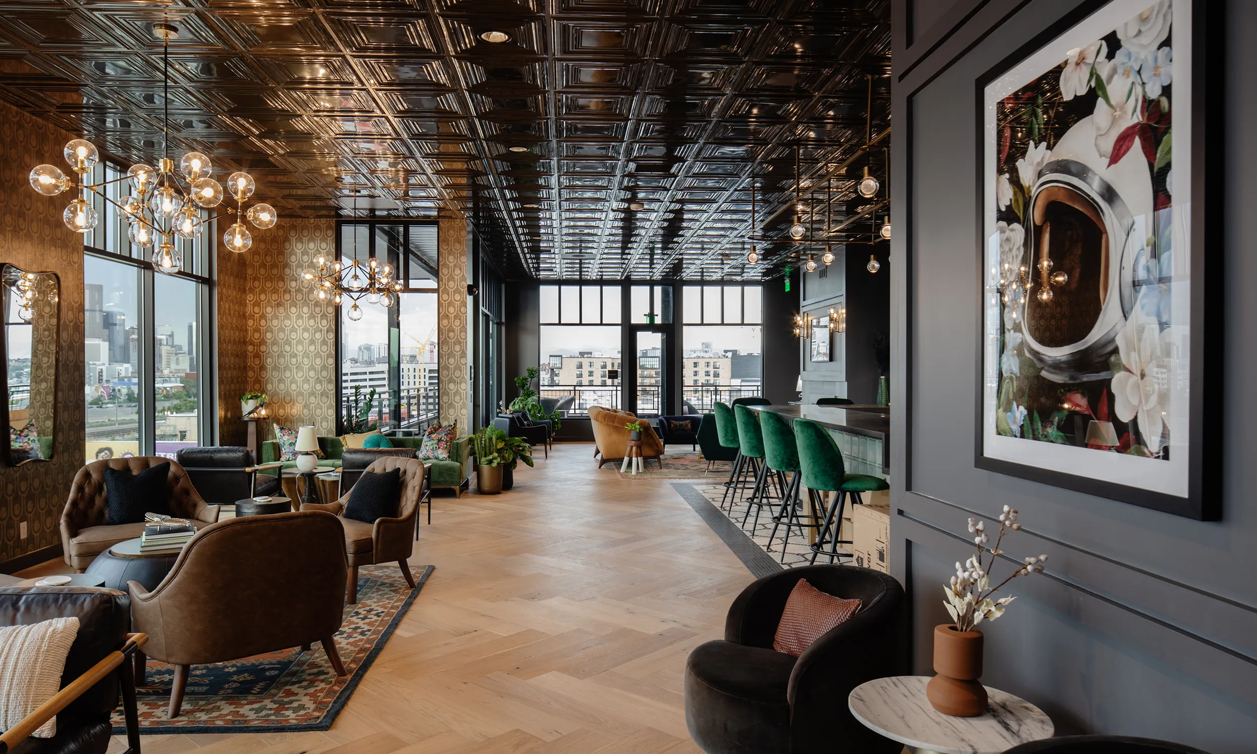 Luxurious lounge with chic modern d&eacute;cor, featuring elegant chandeliers, plush seating, and a stylish bar with green velvet stools, offering panoramic city views modera art park denver co