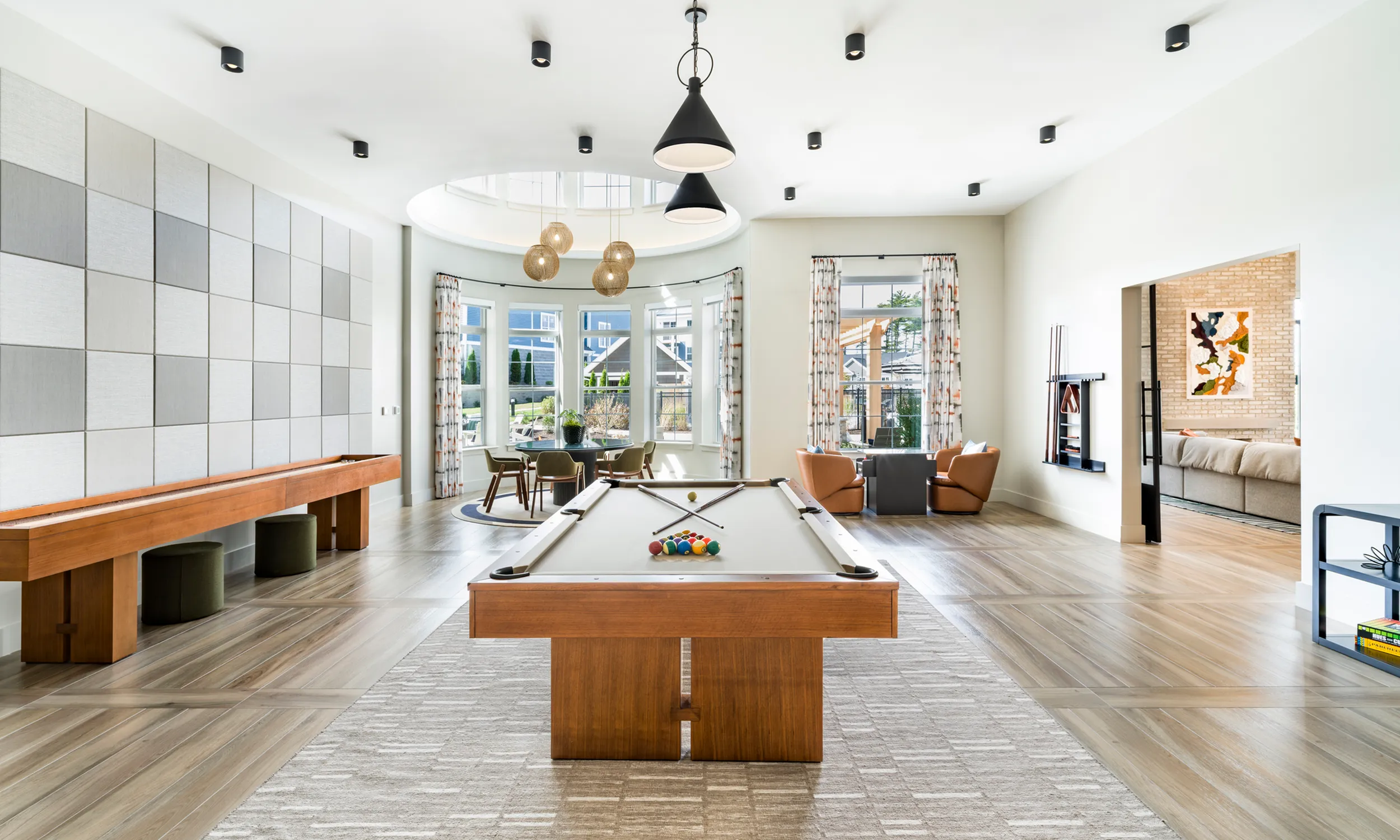 Resident game lounge with modern billiard table, elegant seating, and large, sunlit windows modera south shore apartments for rent marshfield ma