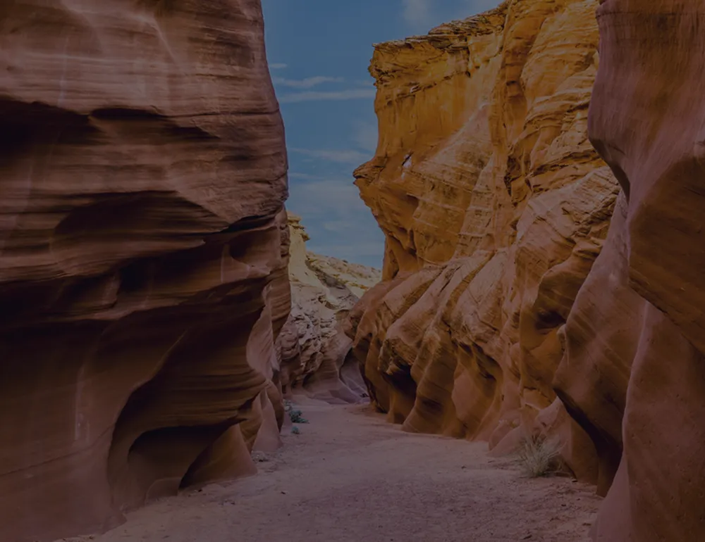 Breathtaking view of a narrow, winding desert canyon with stunning red rock formations and a clear blue sky above.