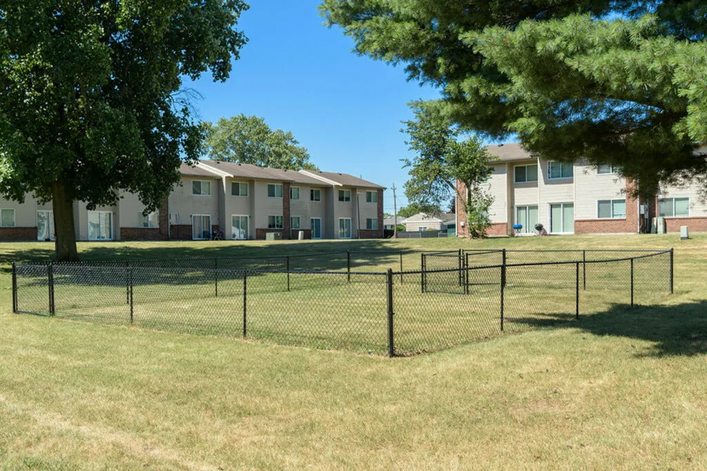 Charming apartment complex with spacious green lawns, mature trees, and inviting outdoor spaces, offering tranquil living.
