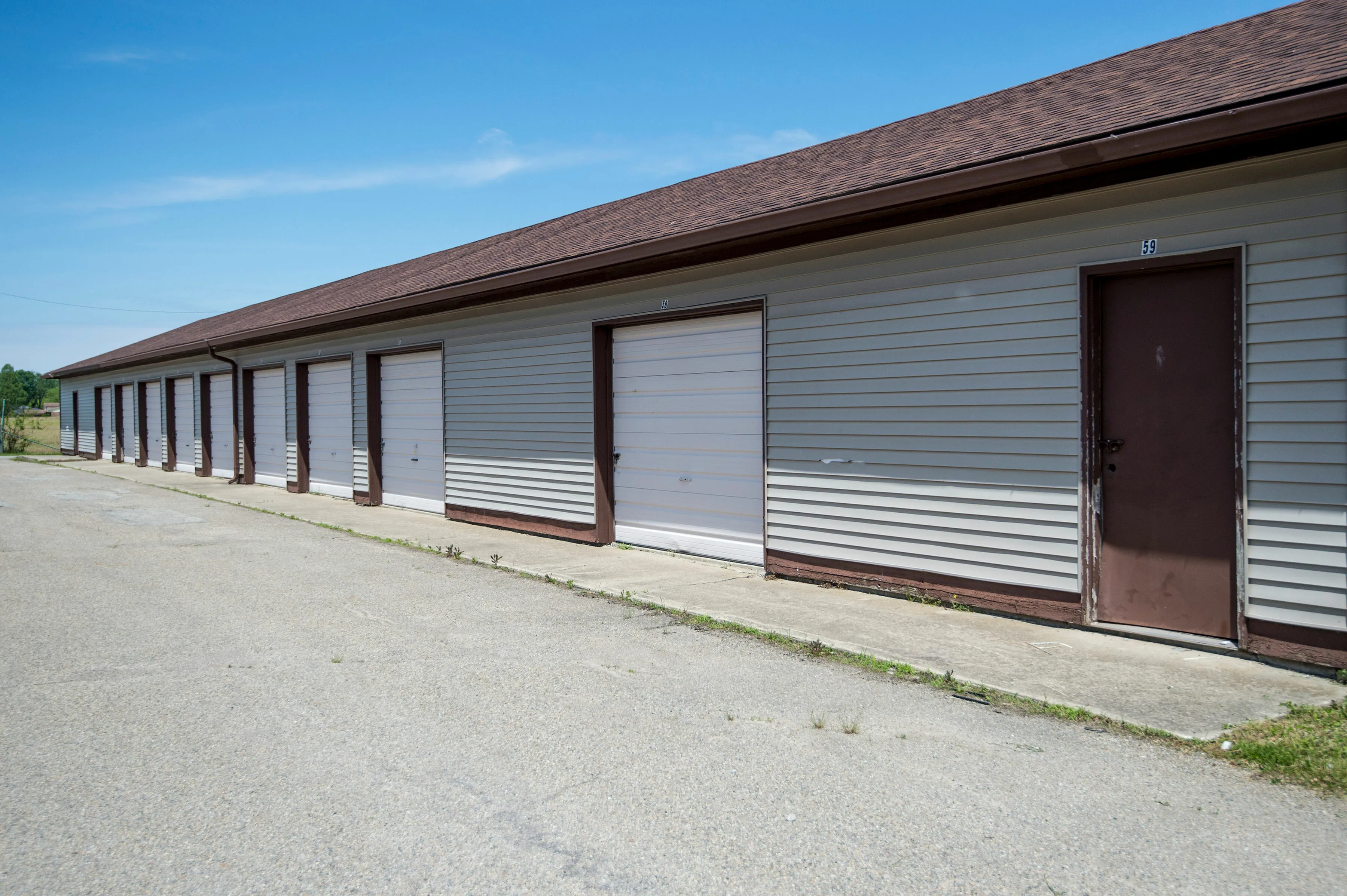 Spacious row of modern garage units with white doors, surrounded by open sky and greenery, ideal for secure storage solutions.