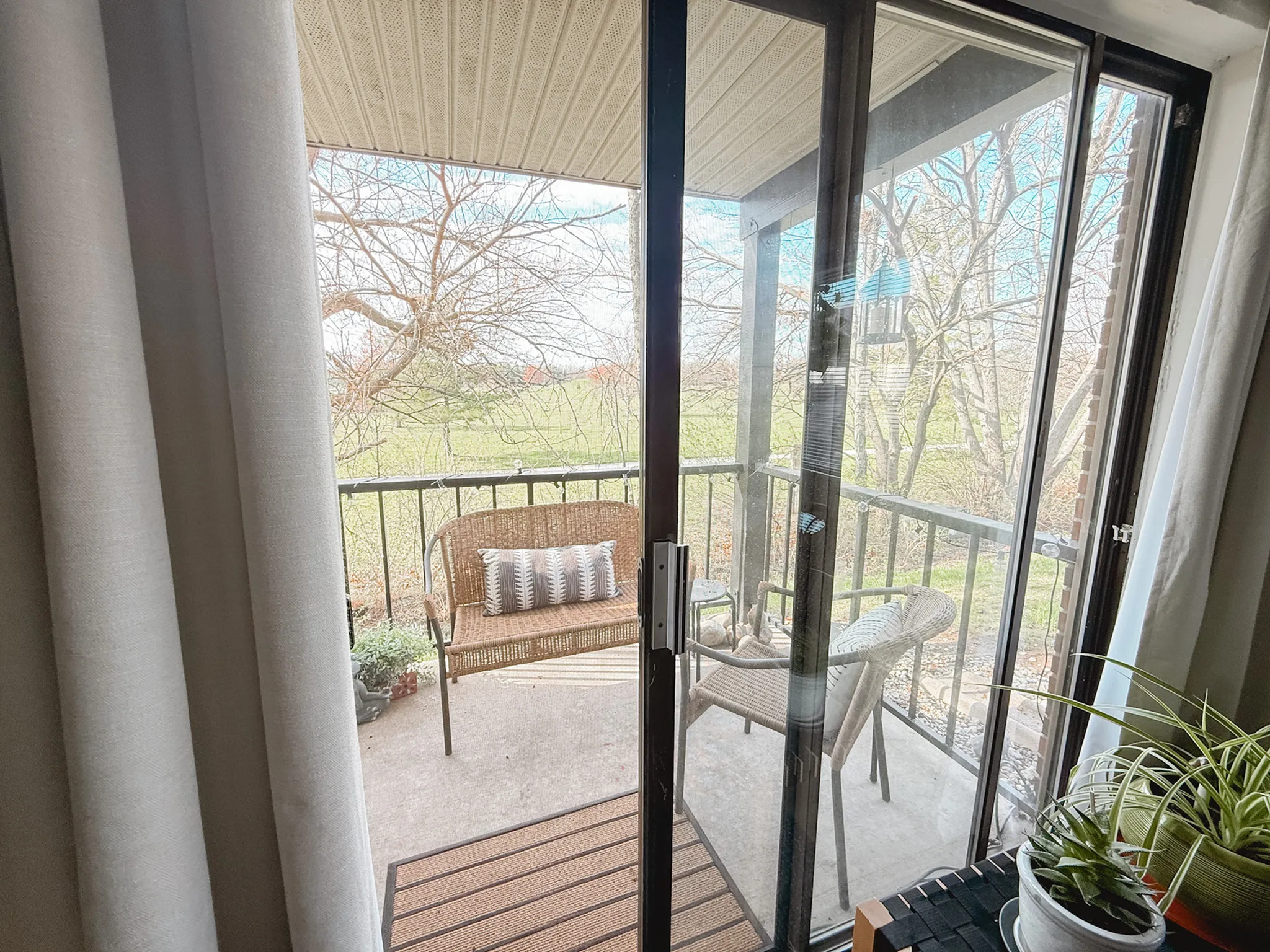 Inviting balcony view with cozy seating and lush greenery, perfect for relaxing outdoors.