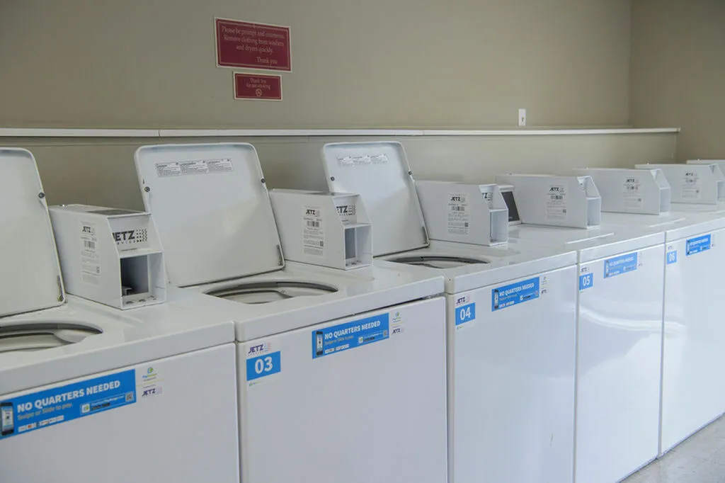 Bright laundry area featuring a row of modern washing machines with convenient coinless operation.