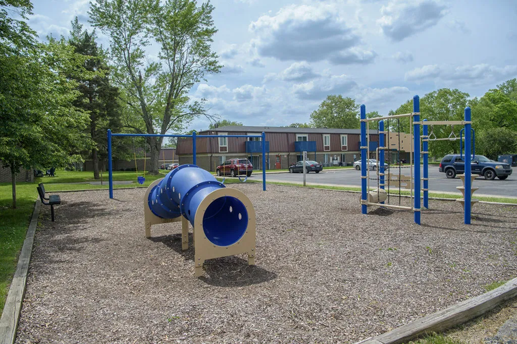 Charming playground amidst lush greenery, offering vibrant blue and beige play structures for family fun and relaxation.
