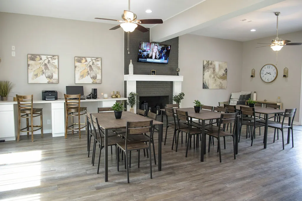 Charming communal area with modern wooden tables, cozy fireplace, and bright decor, perfect for gatherings and relaxation.