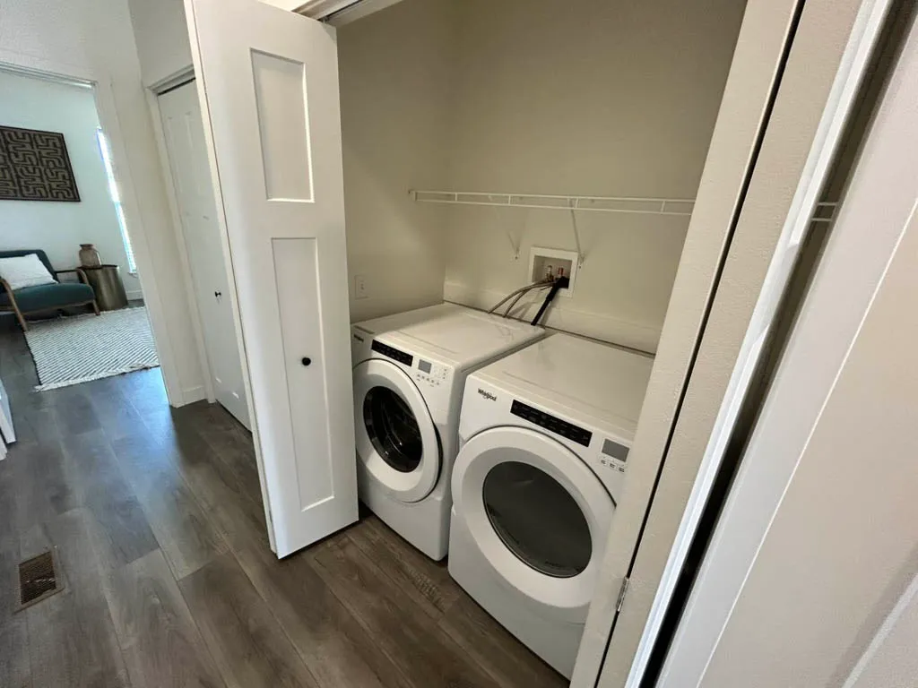 Contemporary laundry nook with modern washer and dryer, adjacent to a stylish living area with chic decor.