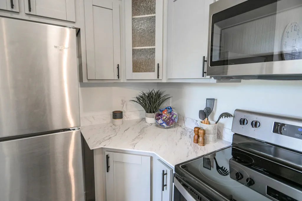 Modern kitchen with sleek stainless steel appliances, elegant marble countertops, and stylish white cabinetry.