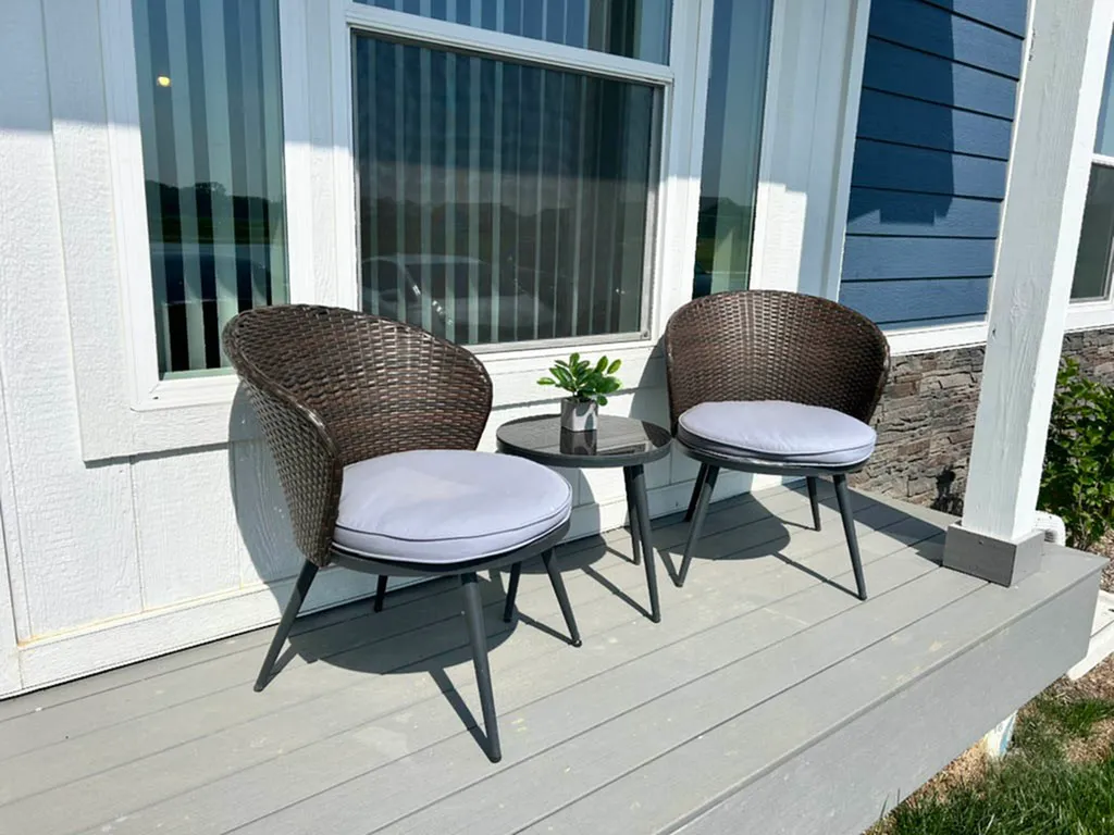 Charming porch with two elegant wicker chairs and a small table, perfect for relaxing outdoors.