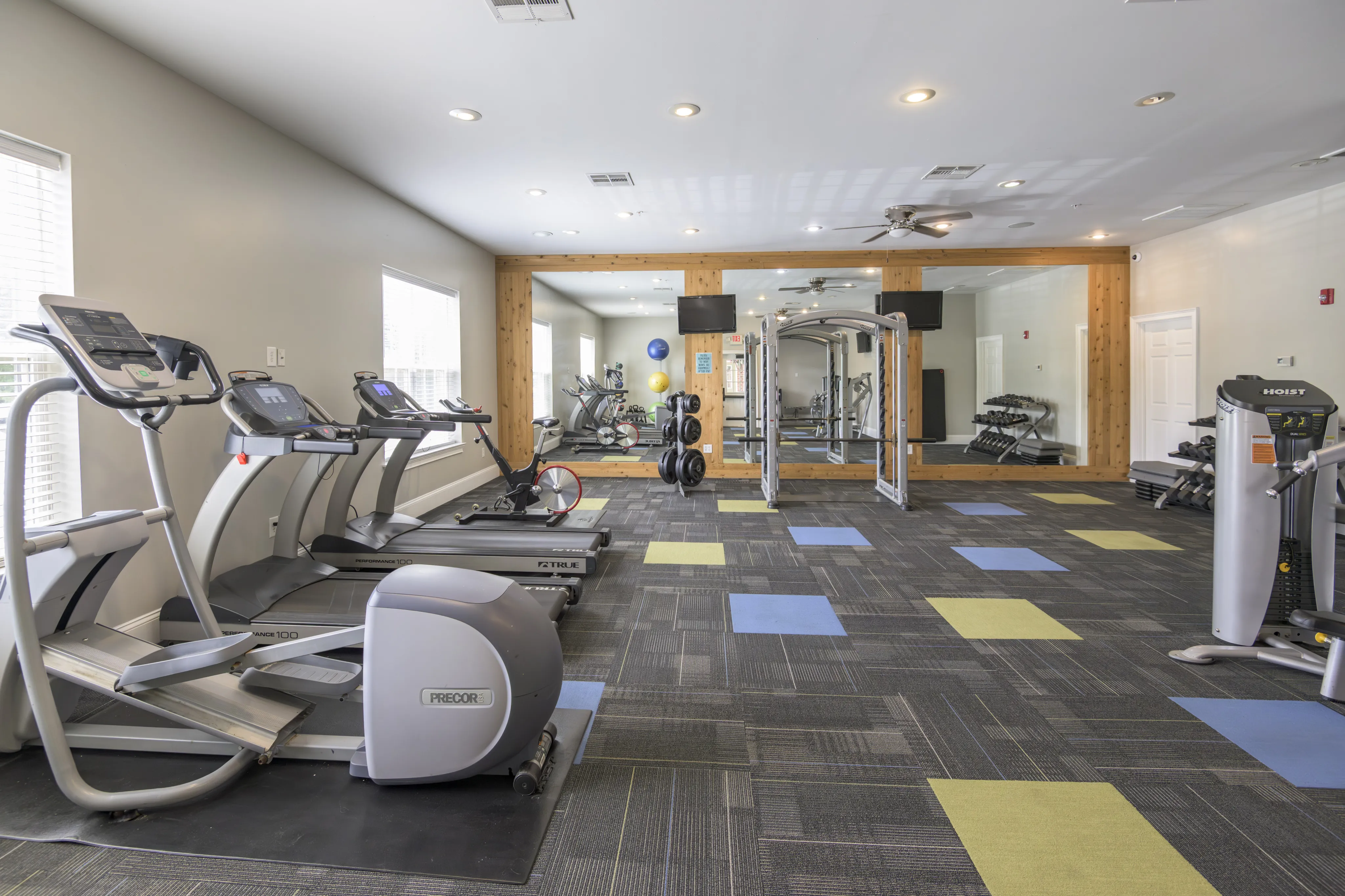 Bright and modern gym with state-of-the-art cardio equipment, mirrored walls, and stylish geometric flooring.