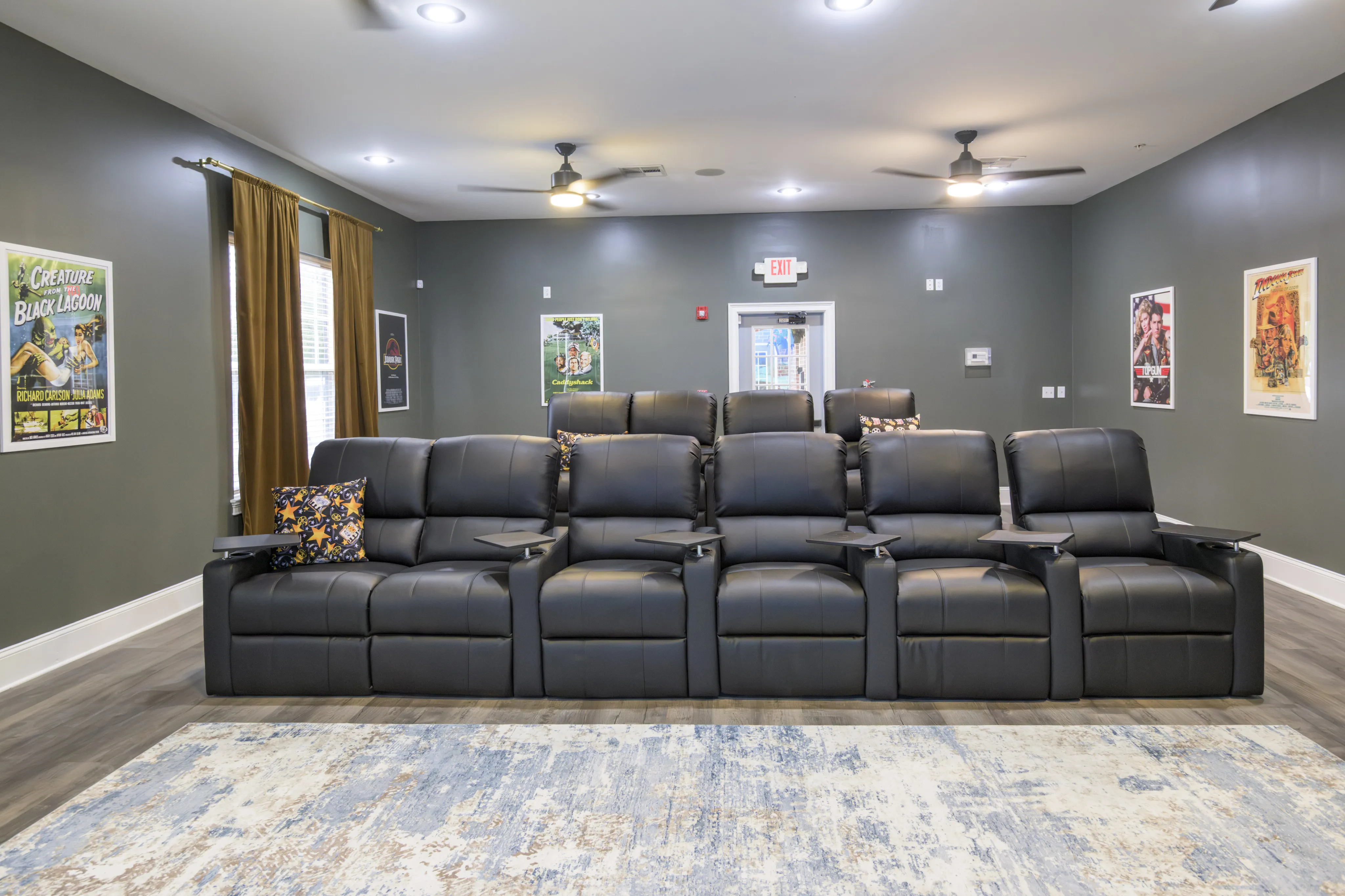Luxurious home theater room with plush black recliners, vibrant wall art, and cozy lighting perfect for movie nights.