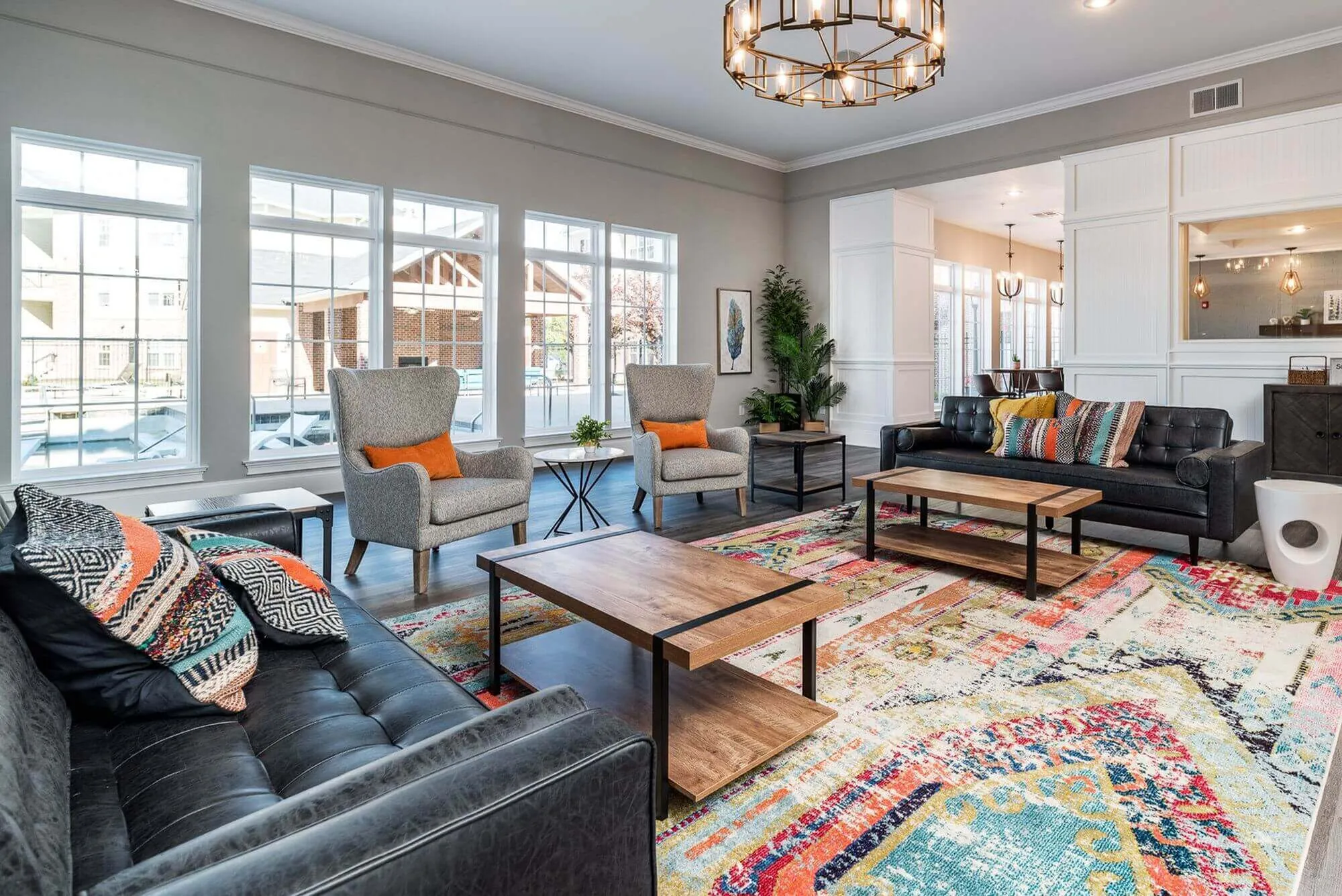 Vibrant, sunlit living room featuring elegant modern furniture, colorful rugs, and large windows offering a scenic view.