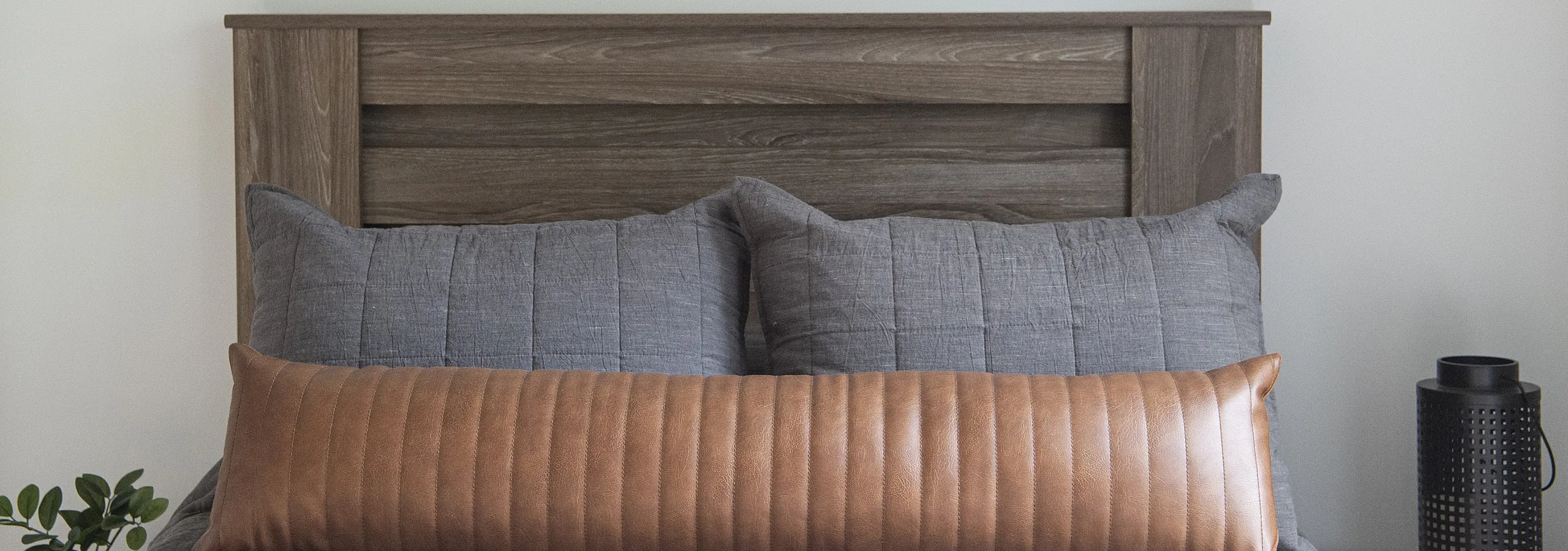 Cozy bedroom featuring a stylish wooden headboard, textured gray pillows, and modern abstract wall art.