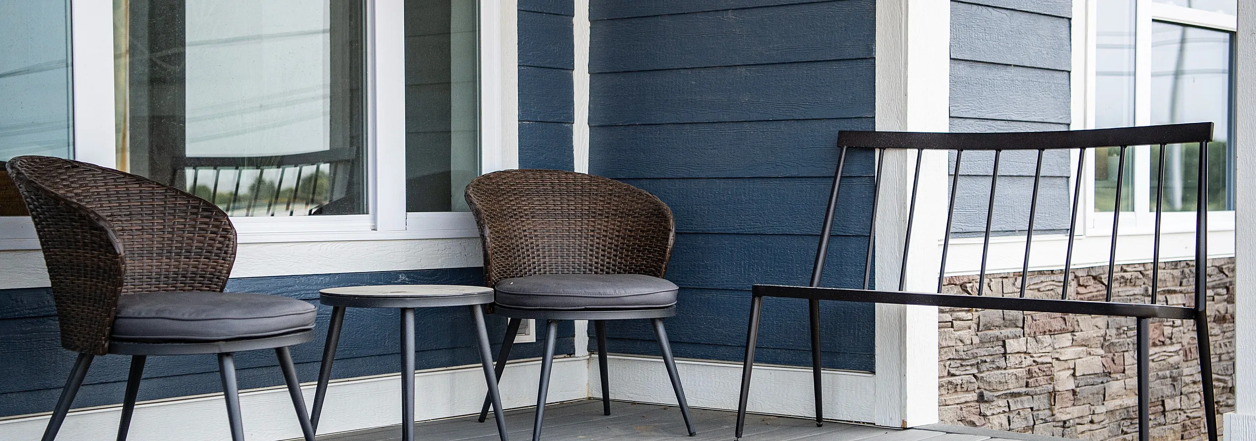 Charming porch scene featuring modern wicker chairs and a sleek bench, perfect for relaxed outdoor enjoyment.