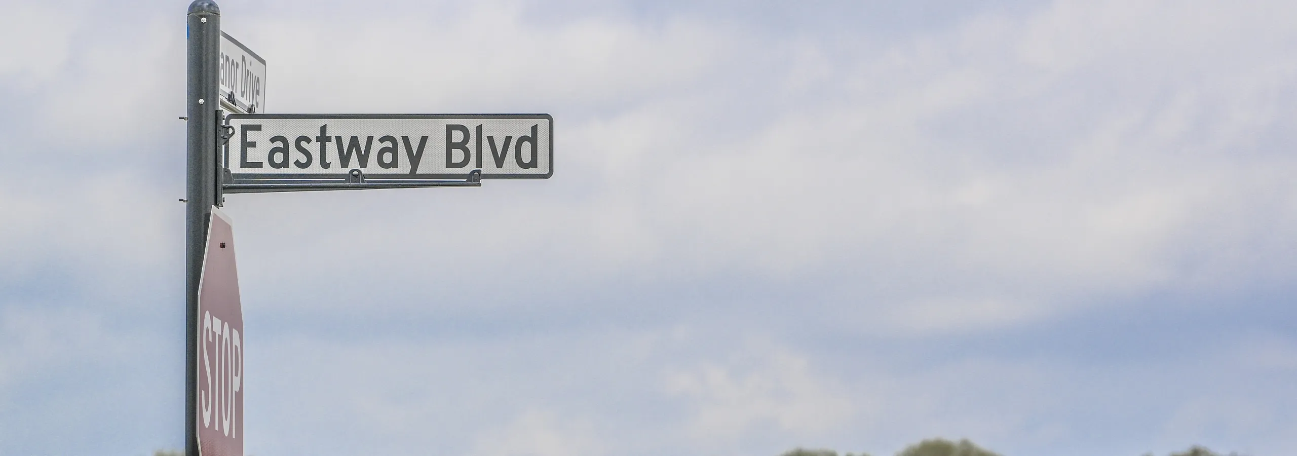 Charming neighborhood view showcasing street signs for Eastway Blvd and quaint rooftops under a vibrant sky.