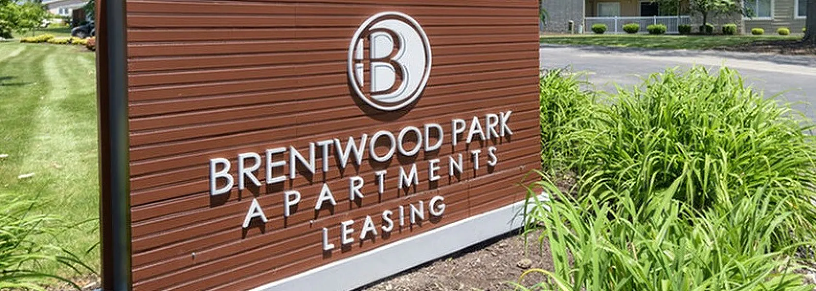 Inviting entrance to Brentwood Park Apartments, featuring lush greenery and modern signage, ideal for comfortable living.