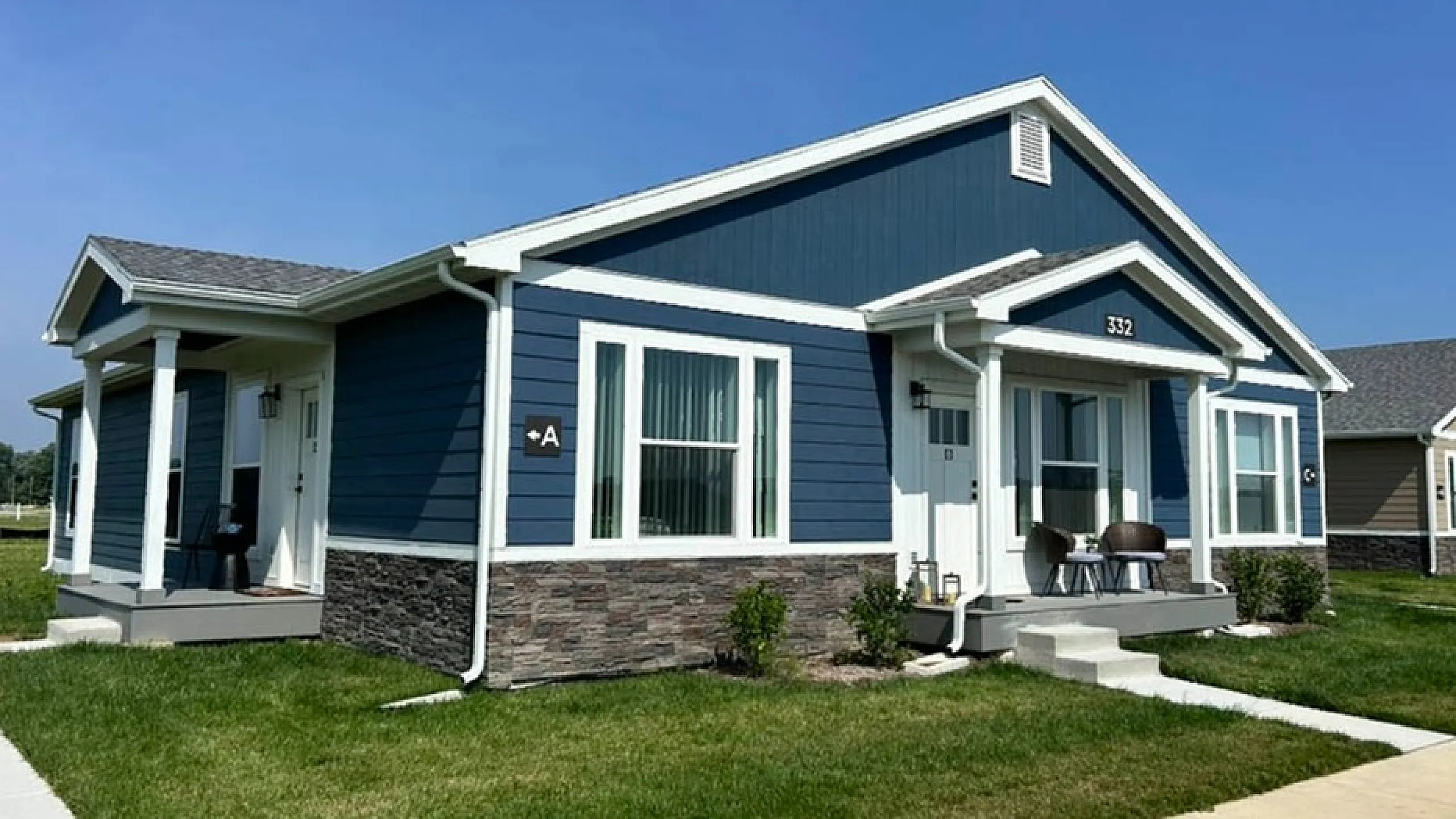 Charming blue and white single-story home with inviting porch and lush green lawn, perfect for tranquil living.