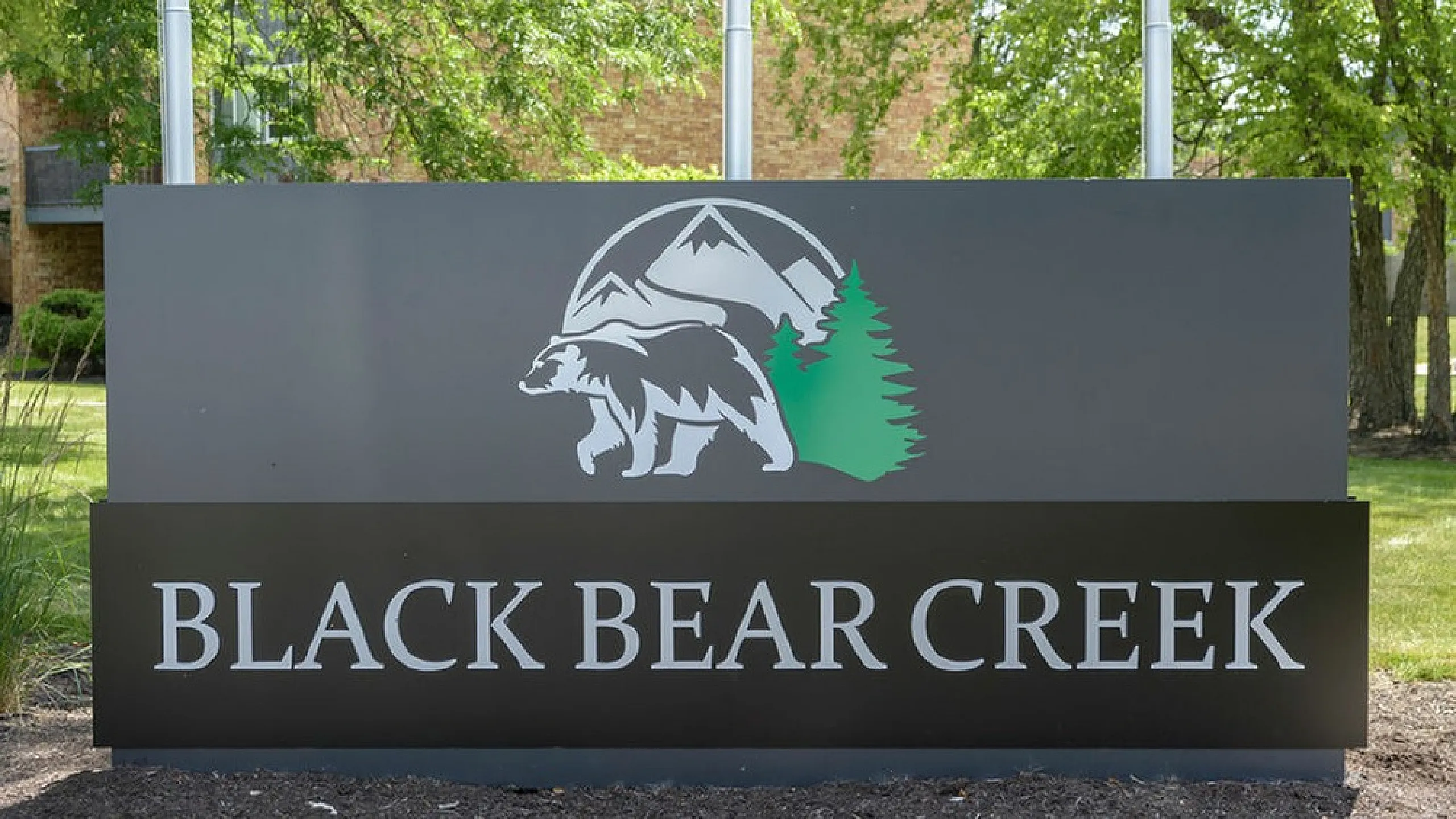 Welcome to Black Bear Creek, featuring a striking sign with nature-inspired design amid lush greenery.