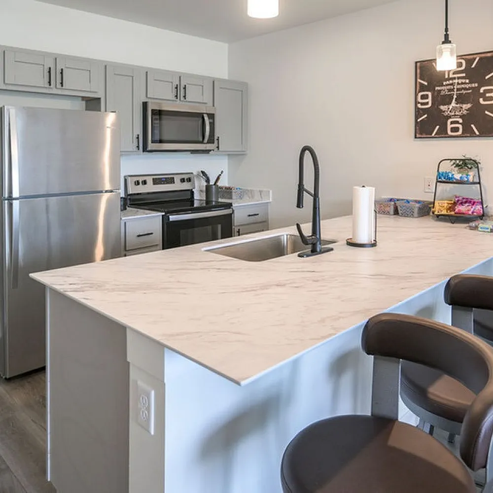 Modern kitchen with sleek stainless steel appliances, elegant marble countertop, and stylish bar seating.