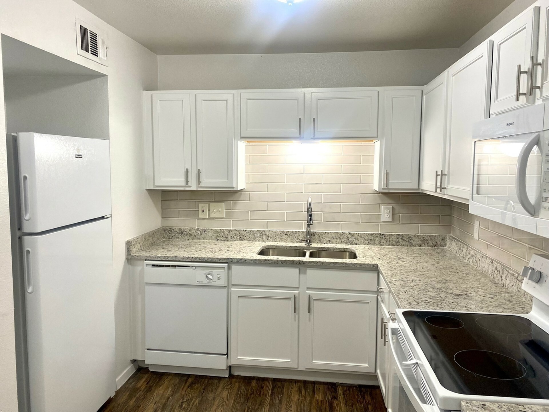 Modern kitchen with sleek granite countertops, white cabinetry, and stainless steel appliances, offering a fresh and inviting cooking space.