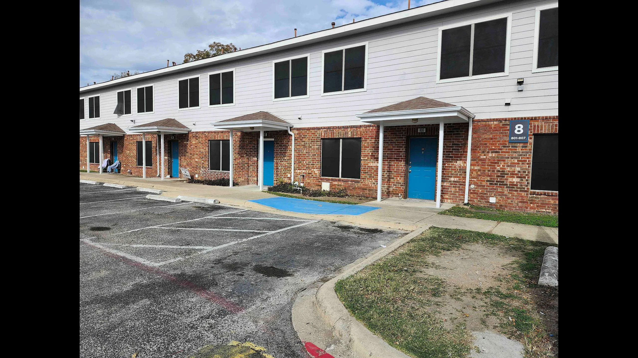 Two-story brick building with blue doors and parking spaces.