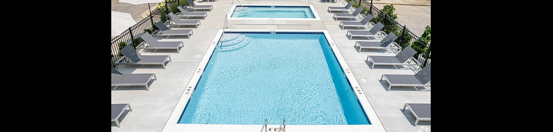 Inviting outdoor swimming pool area with multiple lounge chairs, umbrellas, and a shaded seating space.