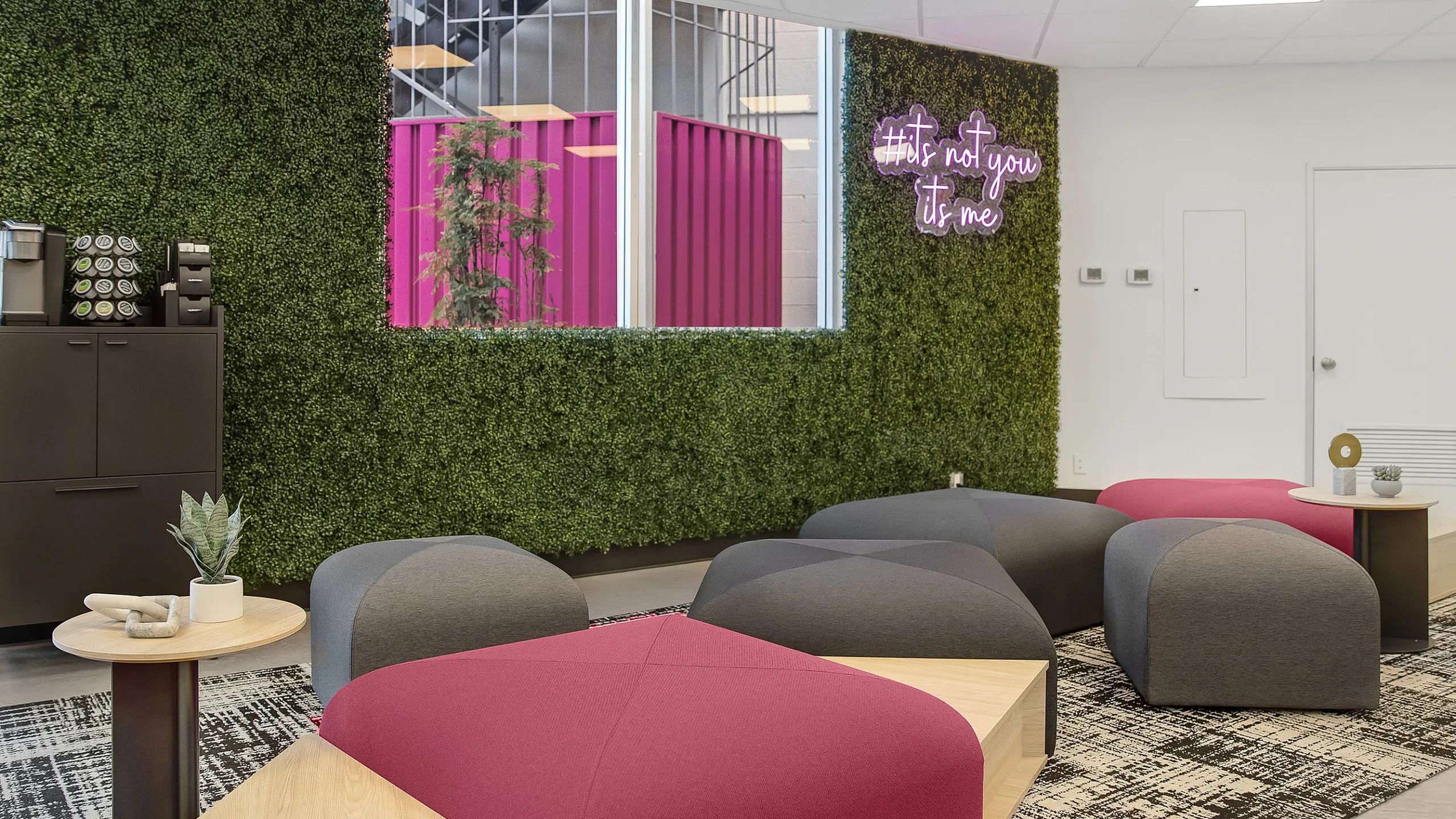 Modern lounge with vibrant seating, lush green wall, and stylish decor creating a cozy atmosphere.