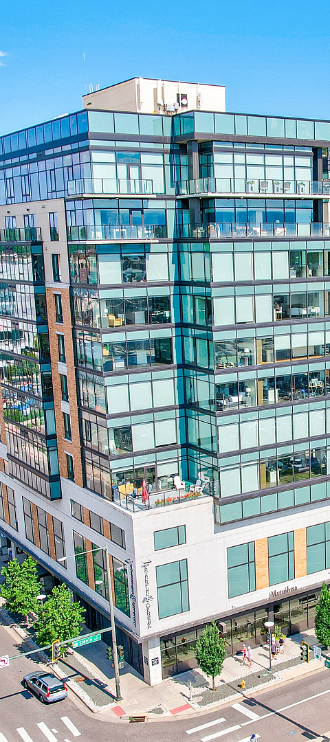 Modern urban apartment complex with sleek glass architecture, featuring lush rooftop gardens and vibrant city views.