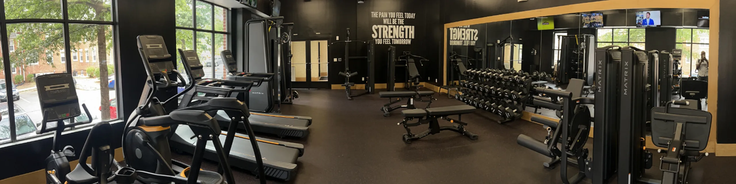 Spacious and modern fitness room featuring state-of-the-art gym equipment, elegant decor, and large windows for natural light.
