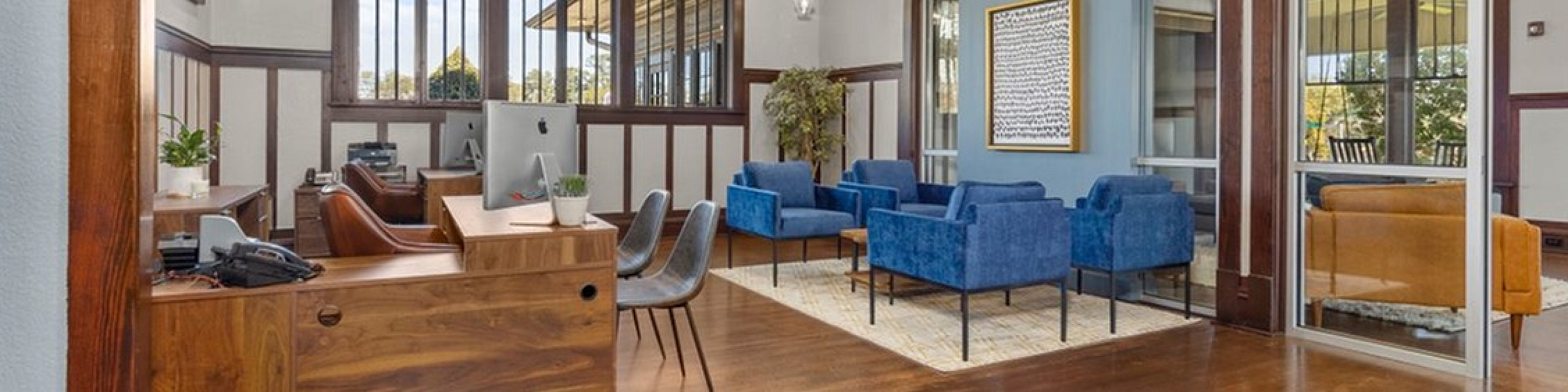 Elegant office space with wooden accents, featuring modern desks and plush blue seating area perfect for collaboration.