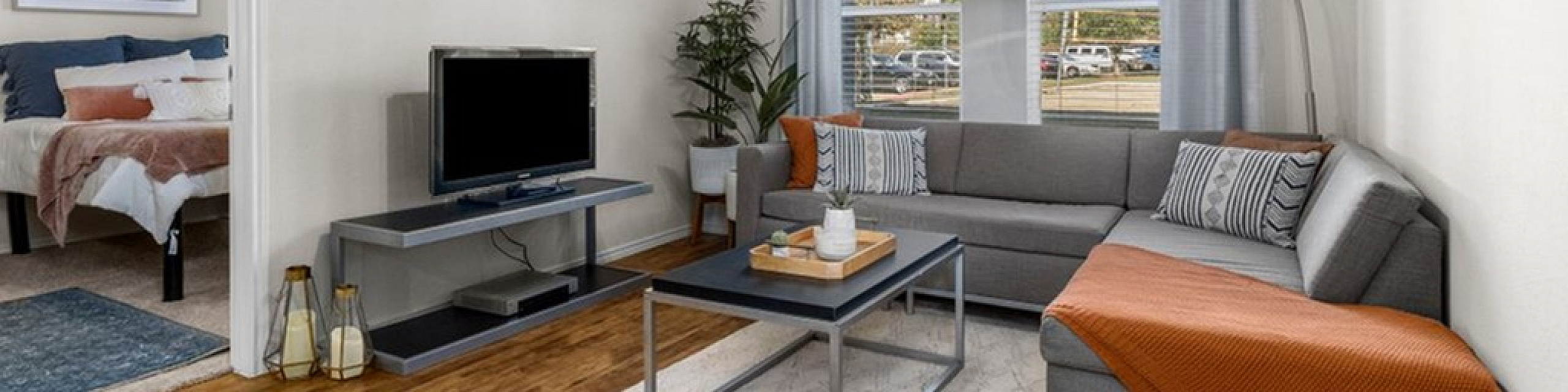 Chic and cozy living room with stylish decor, featuring a comfy sectional sofa, sleek coffee table, and a view into a beautifully appointed bedroom.