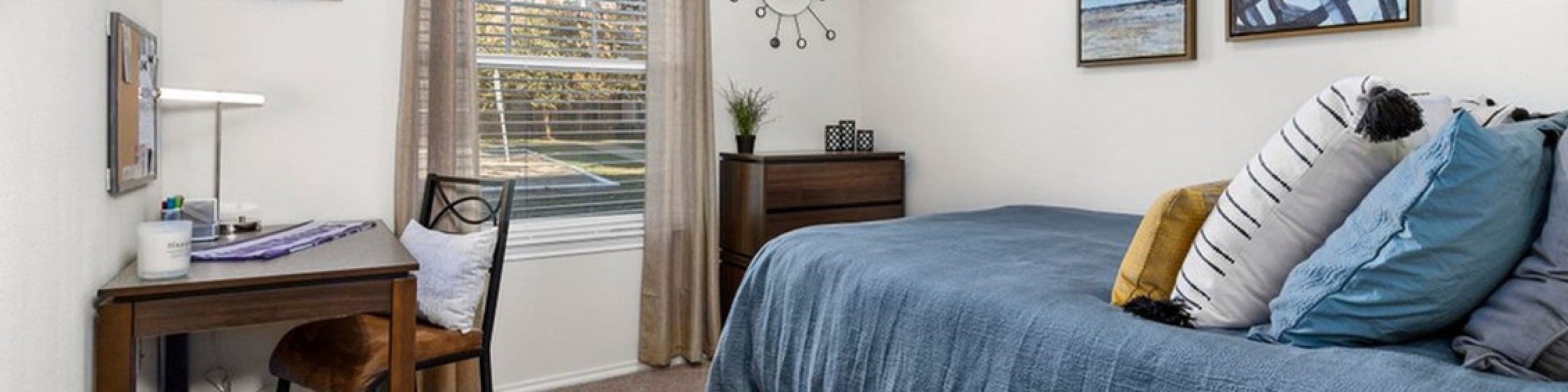 Bright and cozy bedroom with stylish decor, featuring a comfortable bed, charming art on the walls, and a neat workspace by the window.