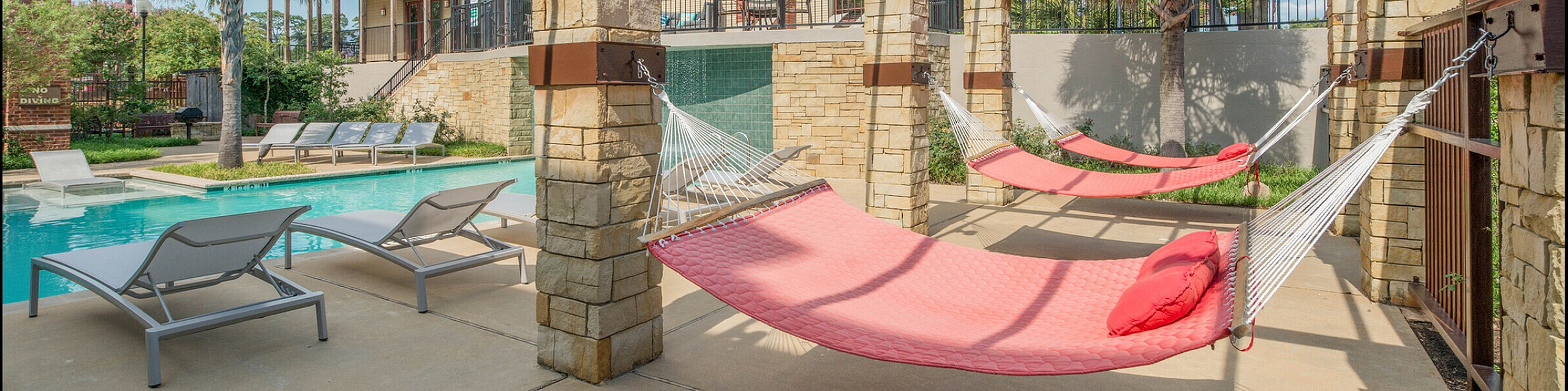 Luxurious outdoor poolside area with stylish lounges, vibrant red hammocks, and a stunning pergola for ultimate relaxation.