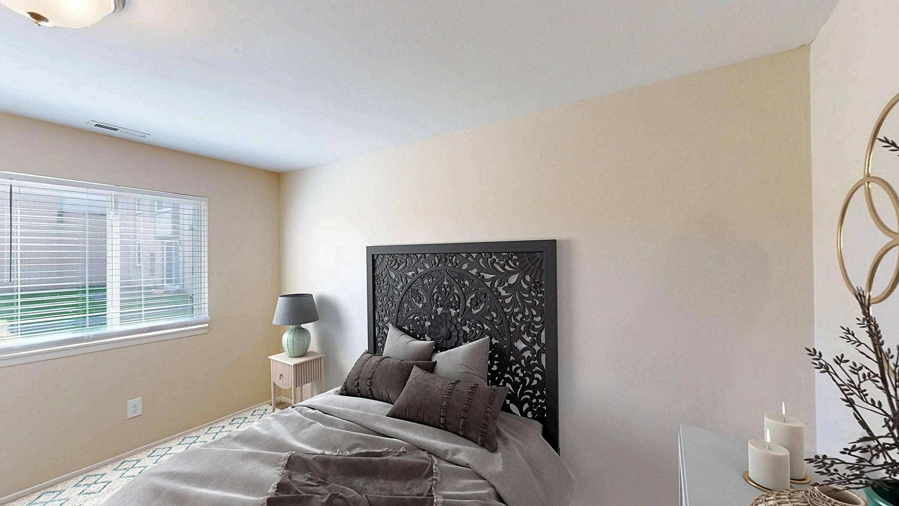 Cozy bedroom with elegant carved headboard, soft ambient lighting, and a tranquil view through large window blinds.