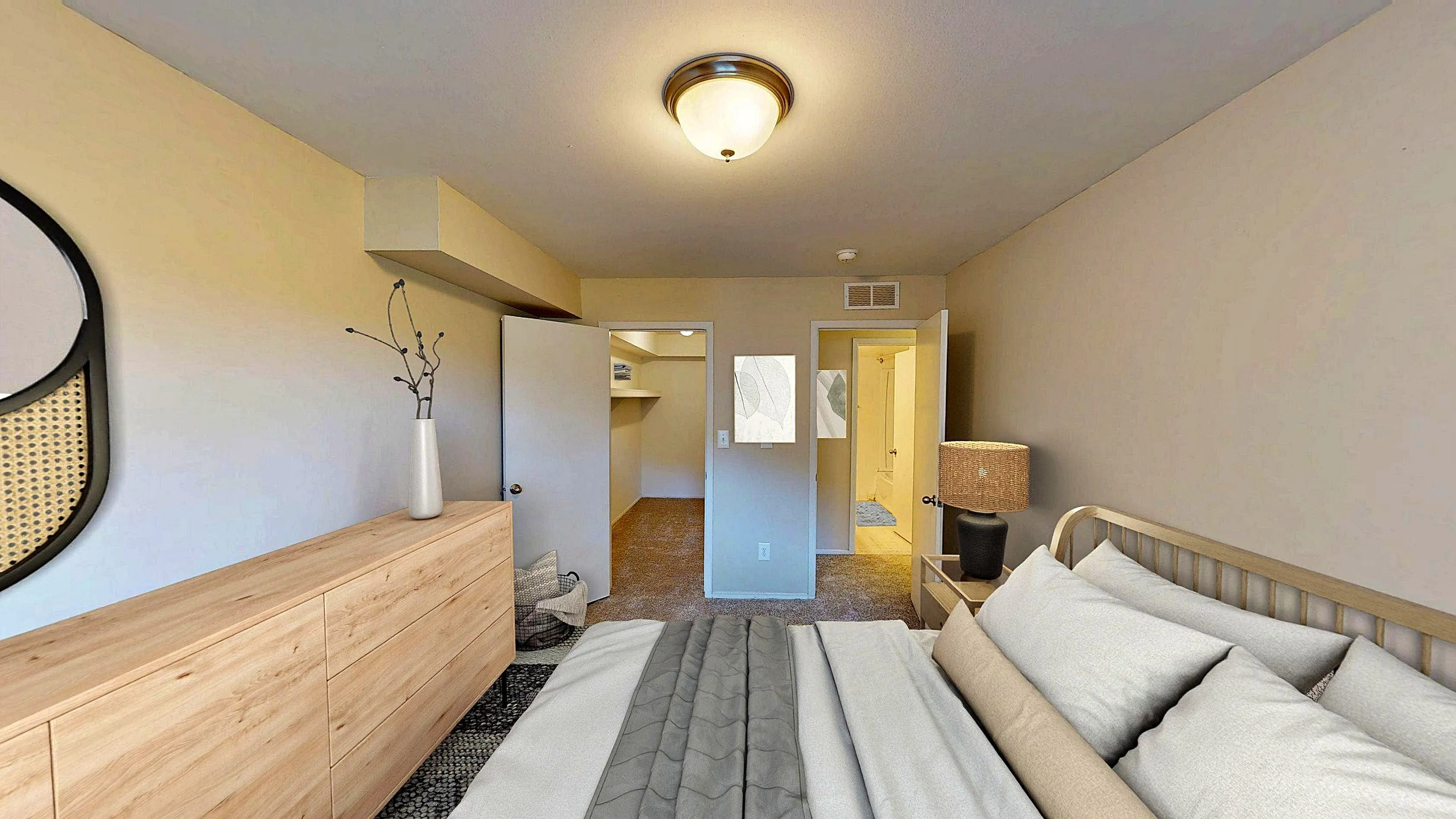 Inviting bedroom with cozy bedding, modern wooden dresser, and a spacious walk-in closet, perfect for stylish living.