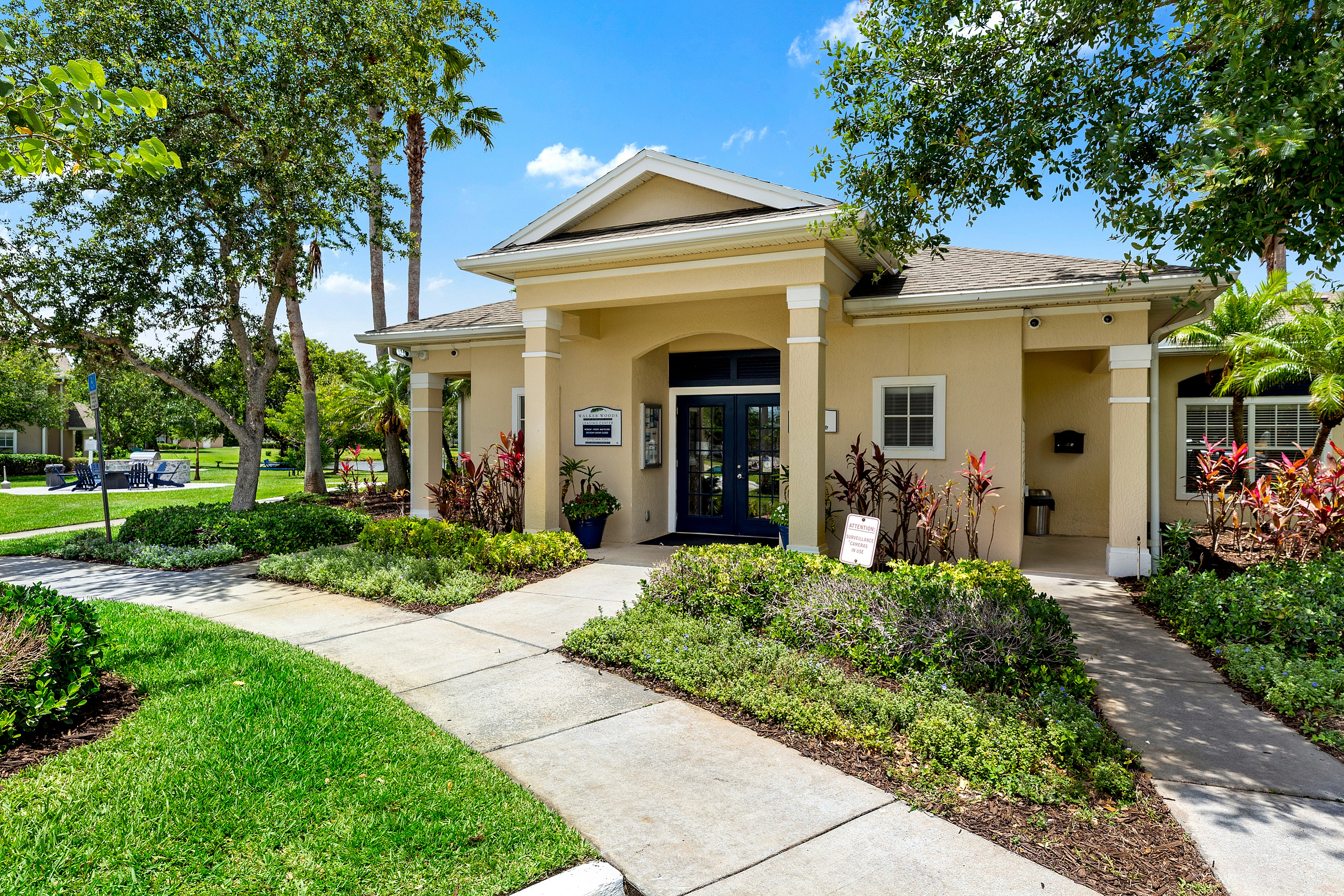 Charming apartment entrance surrounded by lush greenery and vibrant landscaping, offering a welcoming and serene atmosphere.