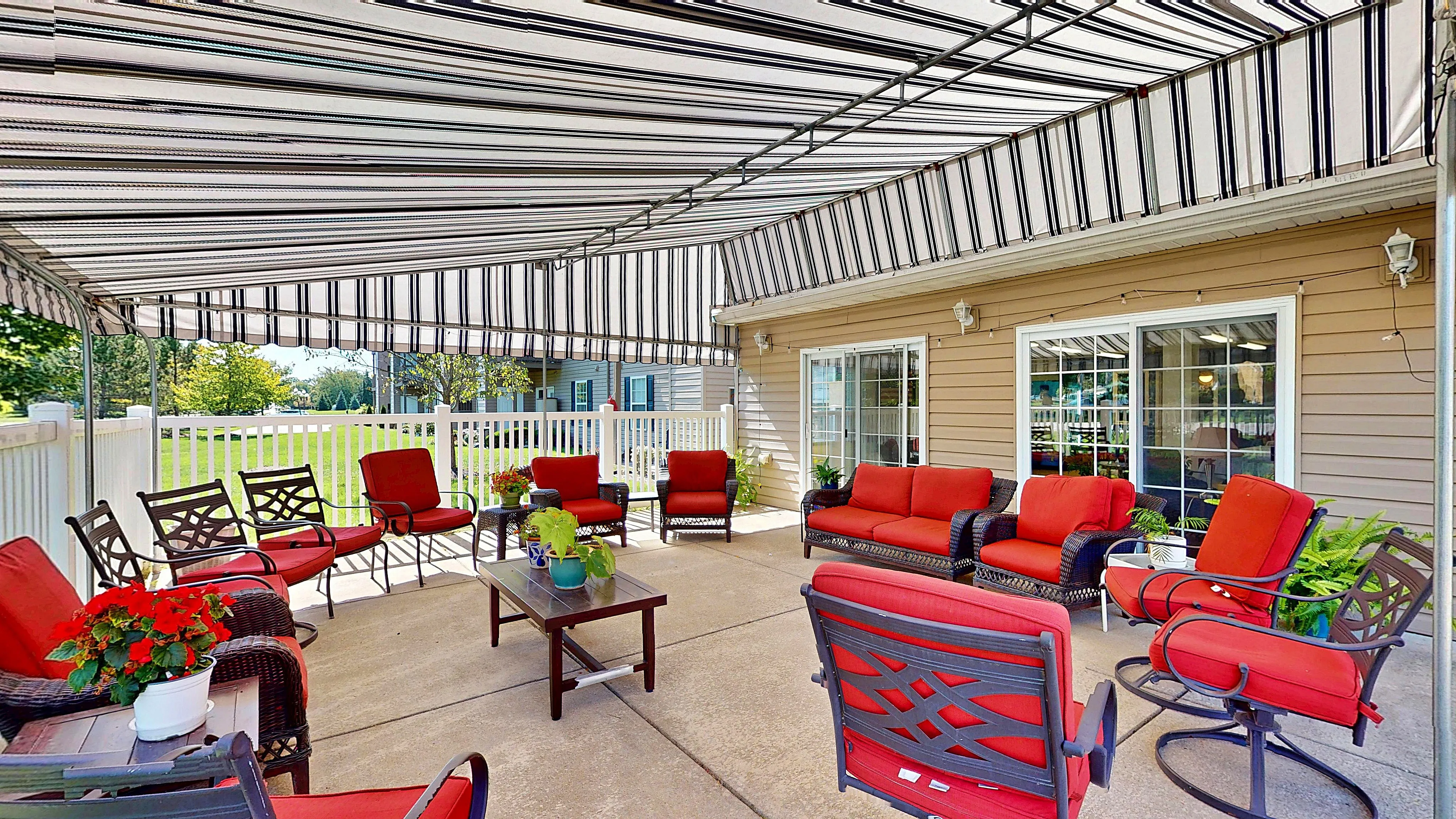Charming outdoor patio with stylish red cushioned seating and inviting striped awning, perfect for relaxation and gatherings.