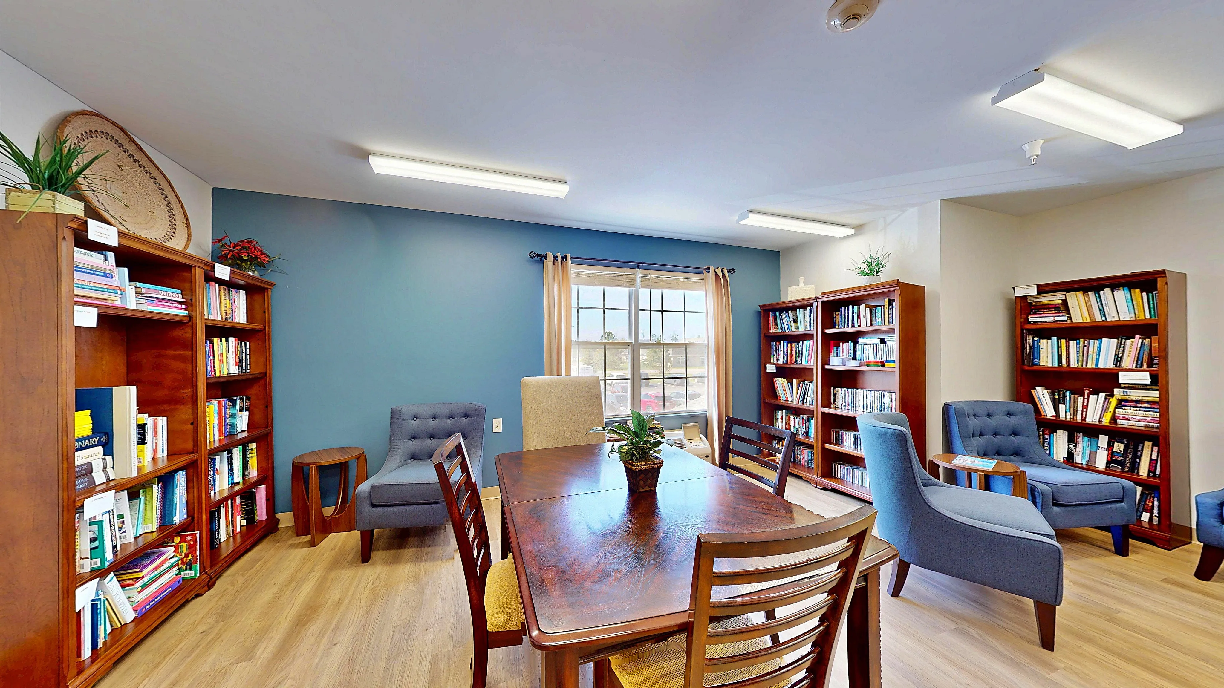 Inviting reading room with elegant wooden bookshelves and plush blue lounge chairs, offering a peaceful retreat.