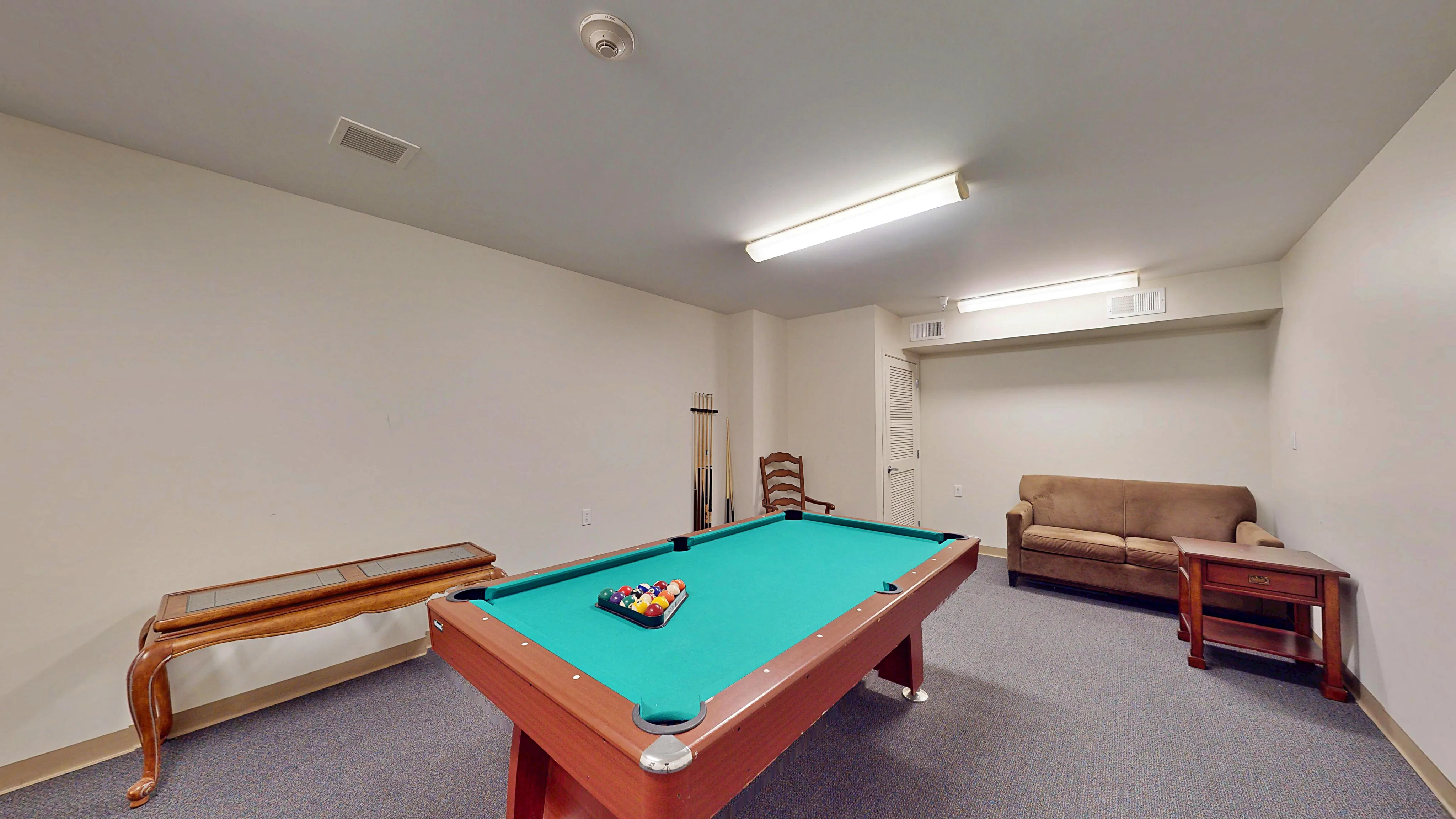 Inviting recreational room featuring a billiard table, cozy sofa, and stylish wood furniture, perfect for entertainment and relaxation.