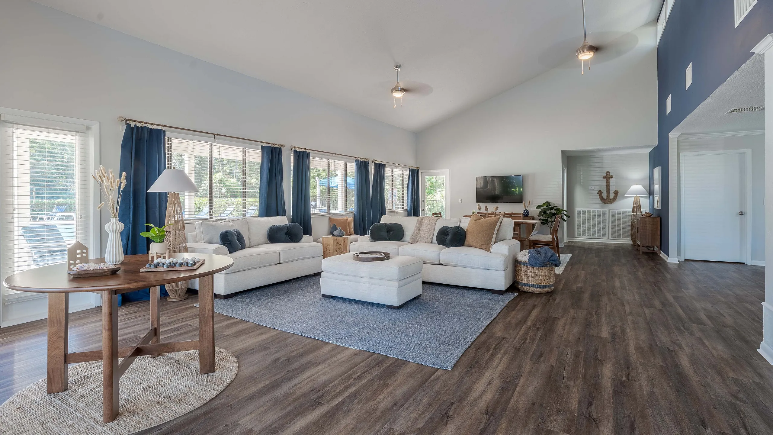 Sophisticated living room with plush sofas, wooden table, and airy ambiance enhanced by large windows.