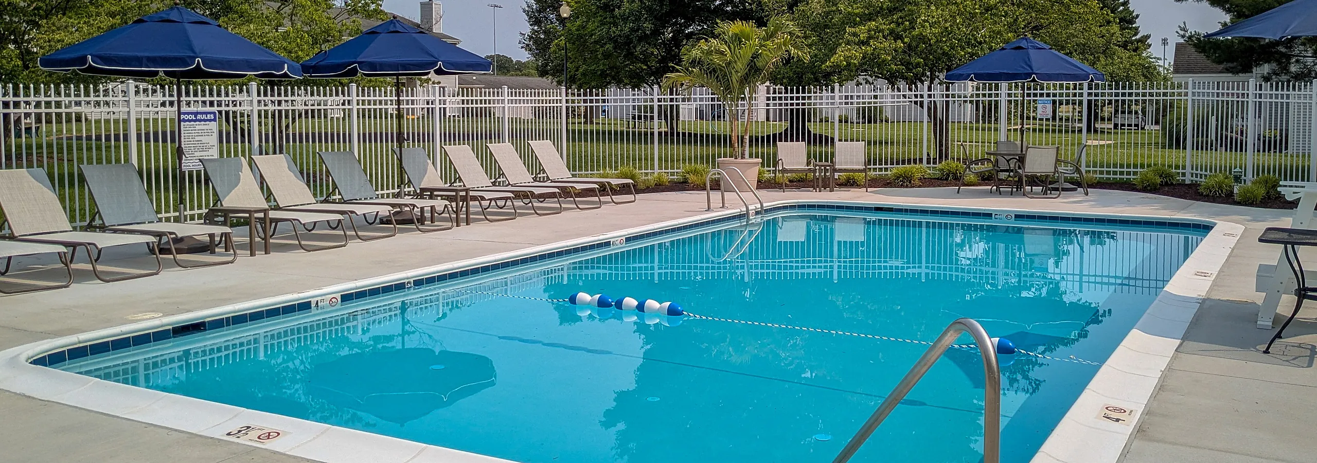 Inviting outdoor swimming pool with comfortable lounge chairs and shaded umbrellas, perfect for relaxation and leisure in a serene setting.