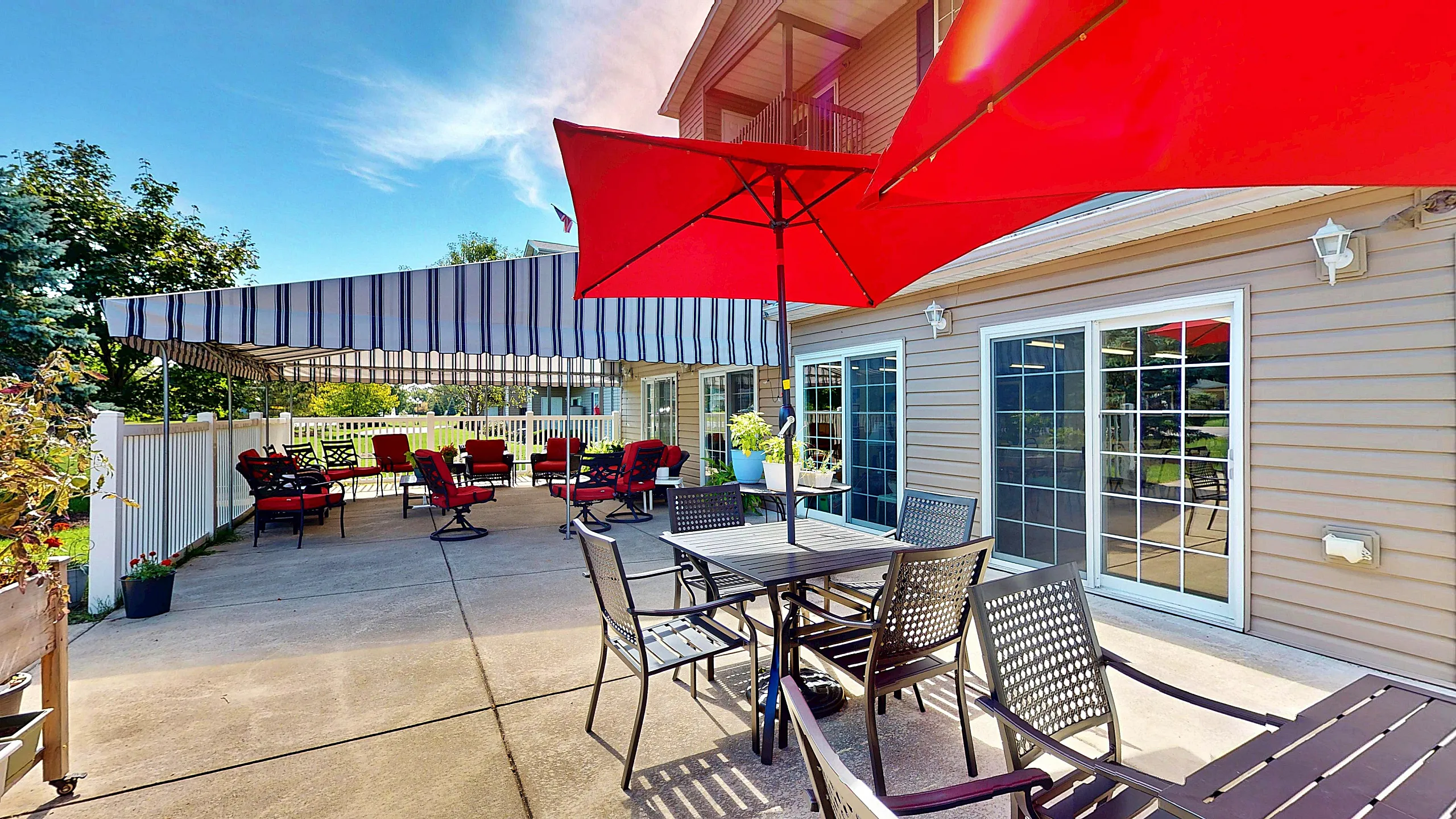 Charming outdoor patio with vibrant red umbrellas and comfortable seating, ideal for relaxing and entertaining on sunny days.