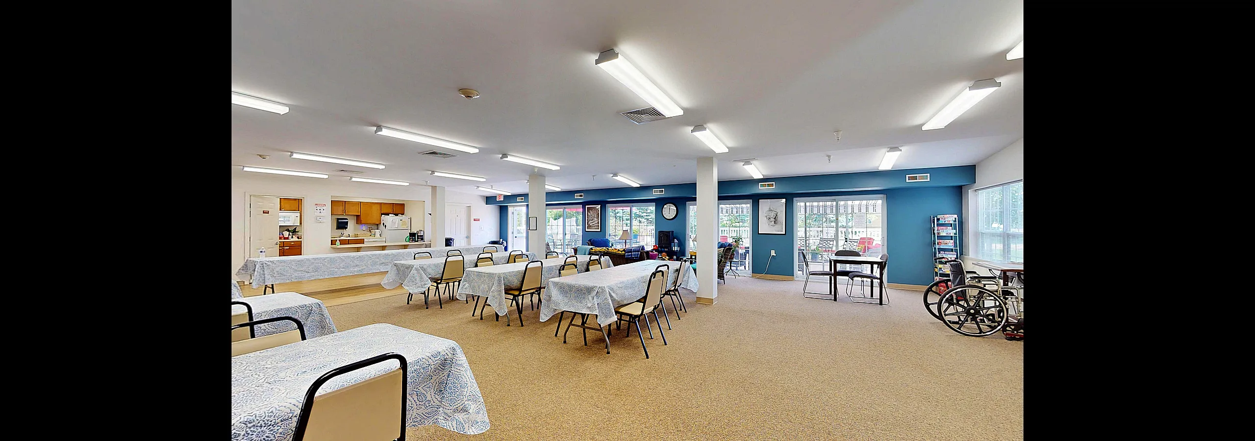 Bright and inviting communal dining area with large windows, multiple tables, and a cozy seating nook, perfect for social gatherings.