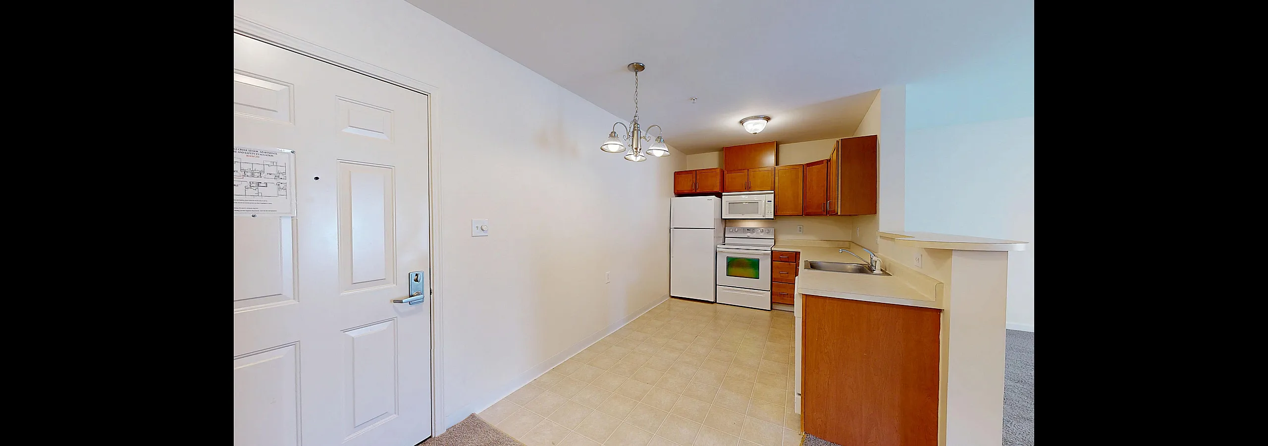 Bright and inviting kitchen with modern appliances, elegant wooden cabinets, and a stylish light fixture creating a warm ambiance.