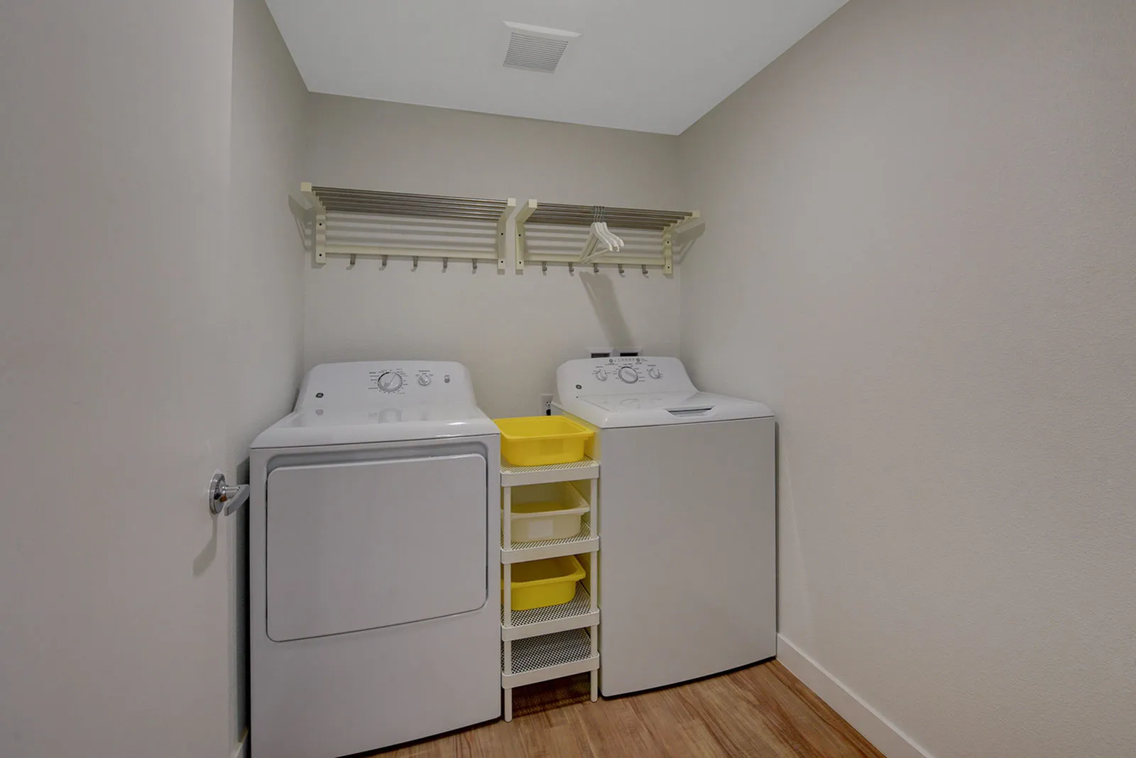 Efficient laundry room featuring a washer and dryer setup with shelving for optimal organization.