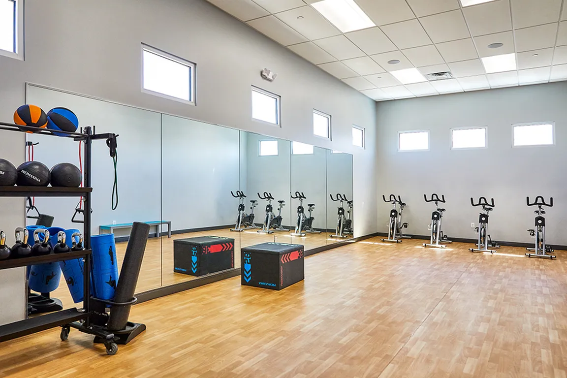 Bright and spacious fitness room with mirrors, exercise bikes, and varied gym equipment.