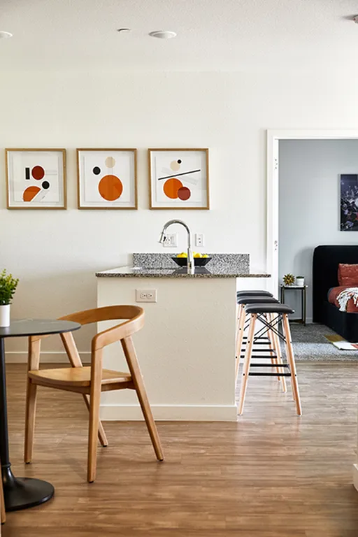 Modern kitchen area with wooden chairs, bar stools, and abstract artwork on the walls.