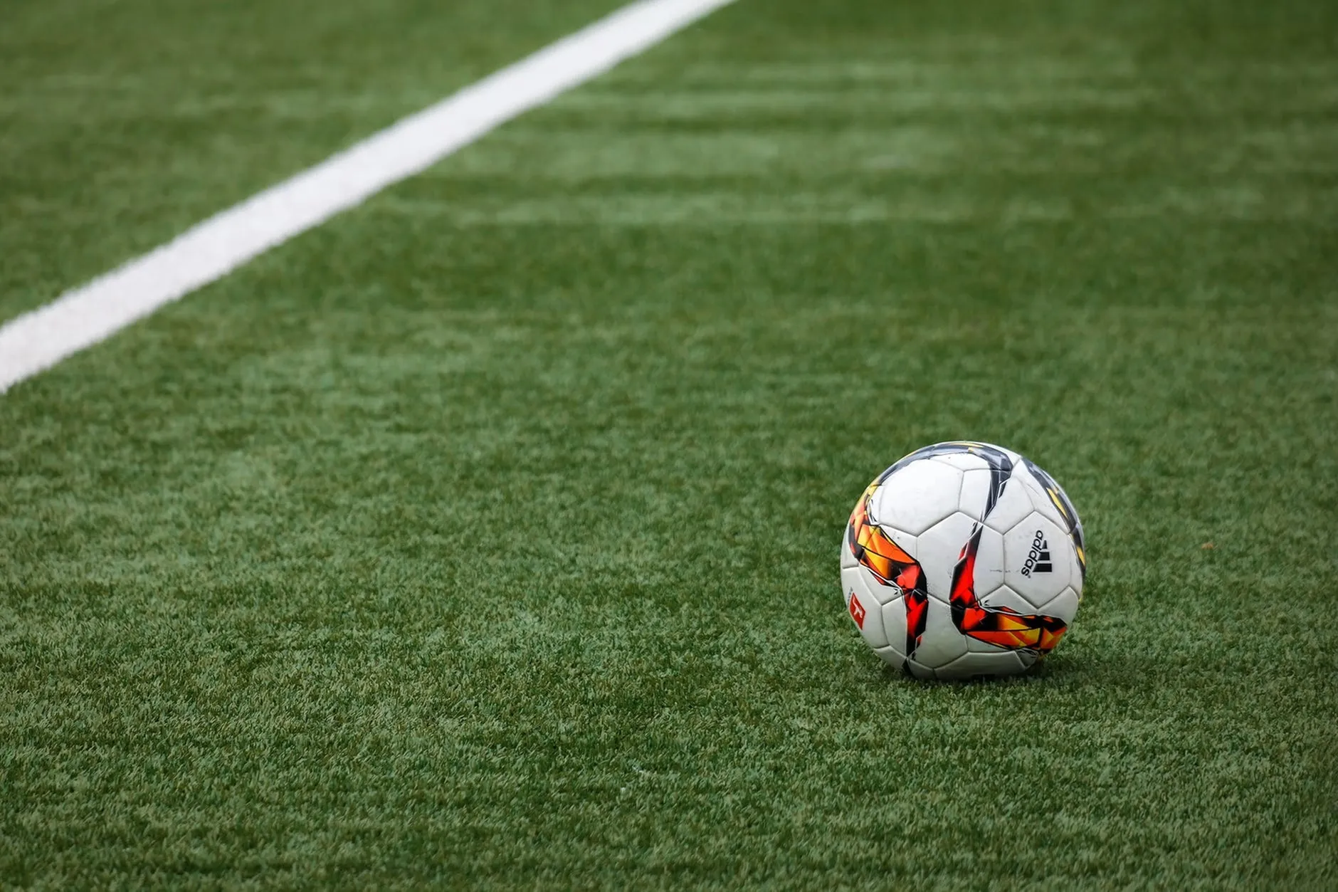 Vibrant green soccer field with a colorful soccer ball near the sideline.