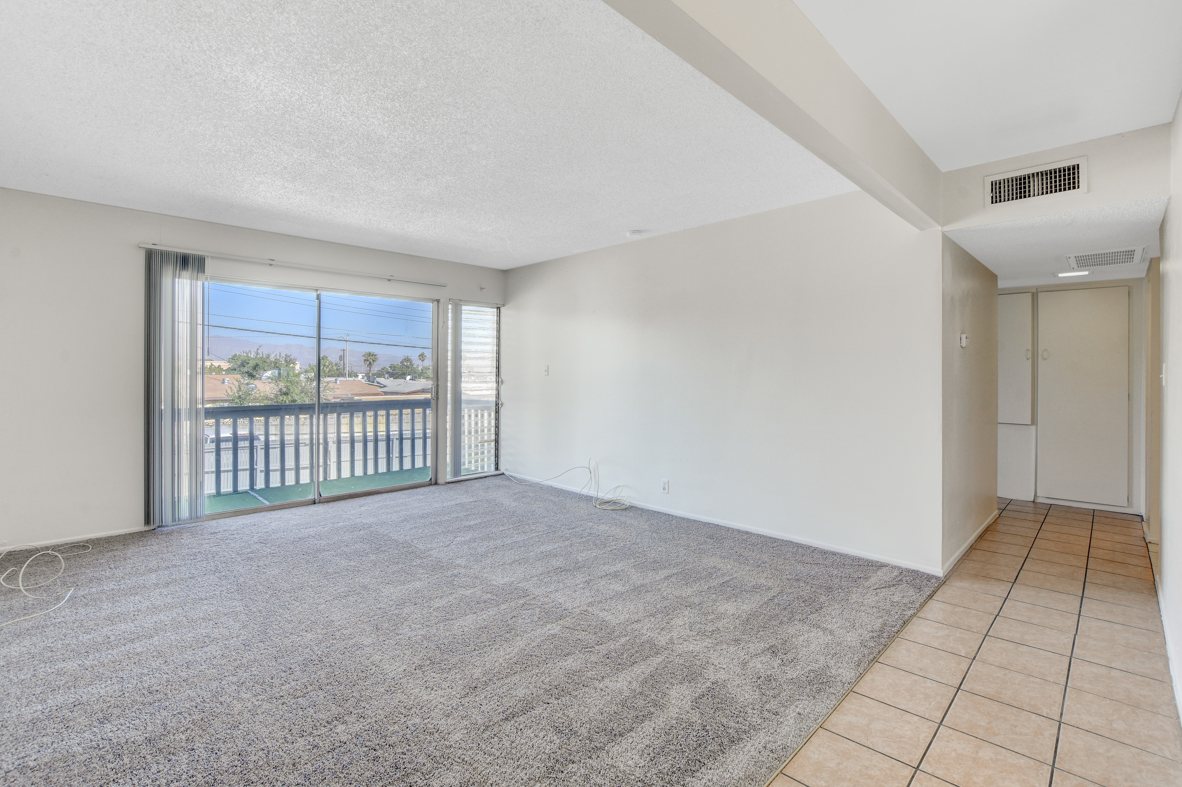 Spacious living room with plush carpet, large sliding glass doors leading to a balcony with scenic views.