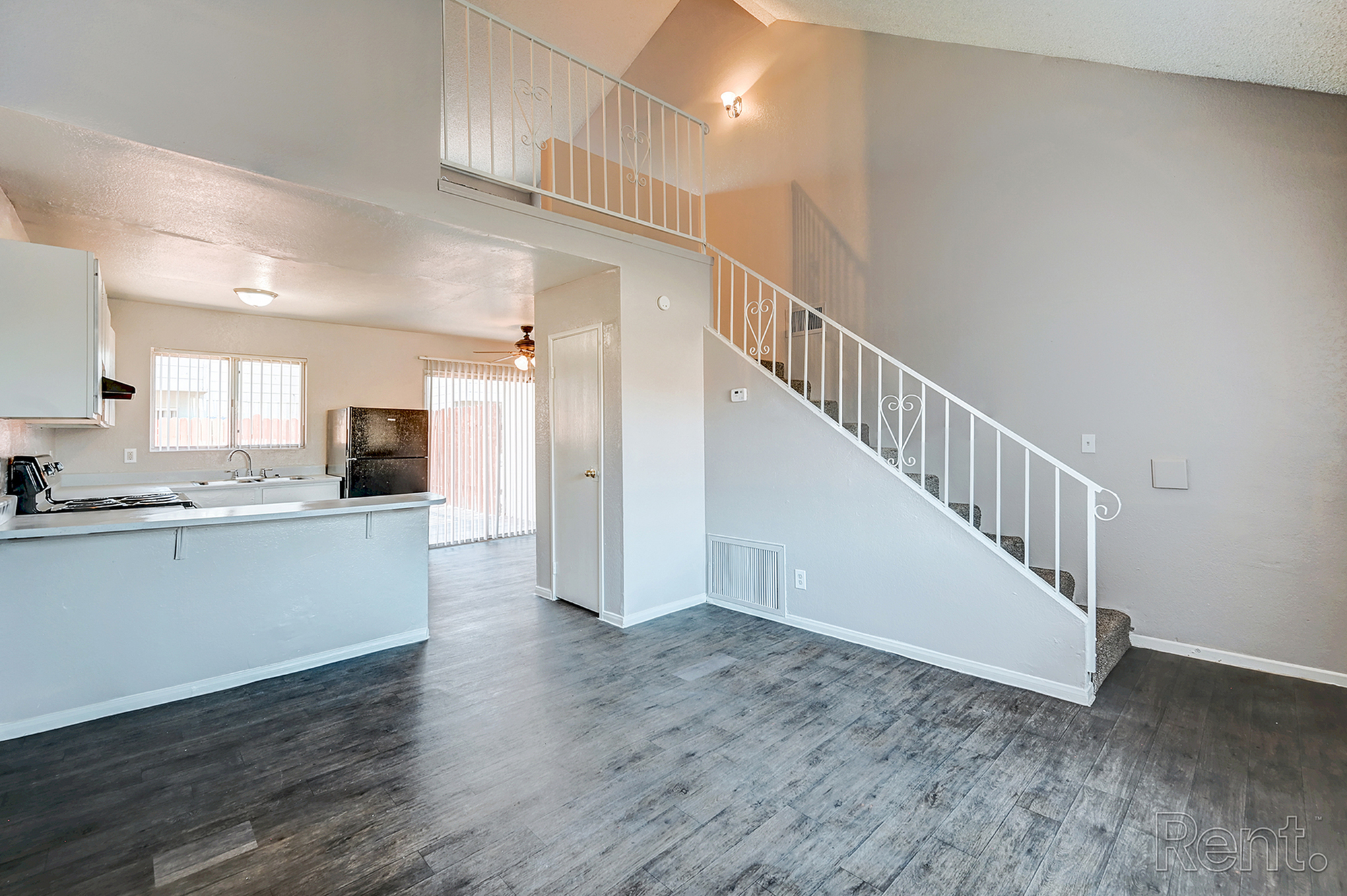 Bright open-concept kitchen and living area with modern flooring and elegant staircase.