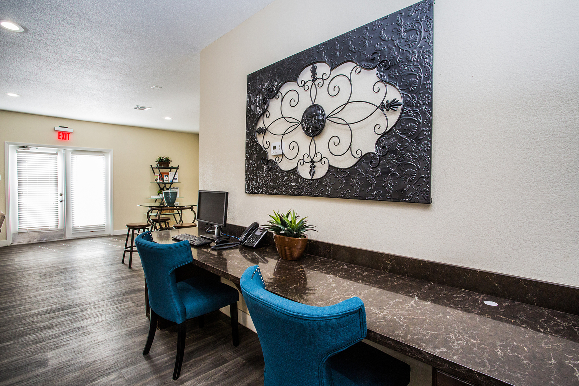 Chic office corner with elegant blue chairs, modern desk, and decorative wall art.